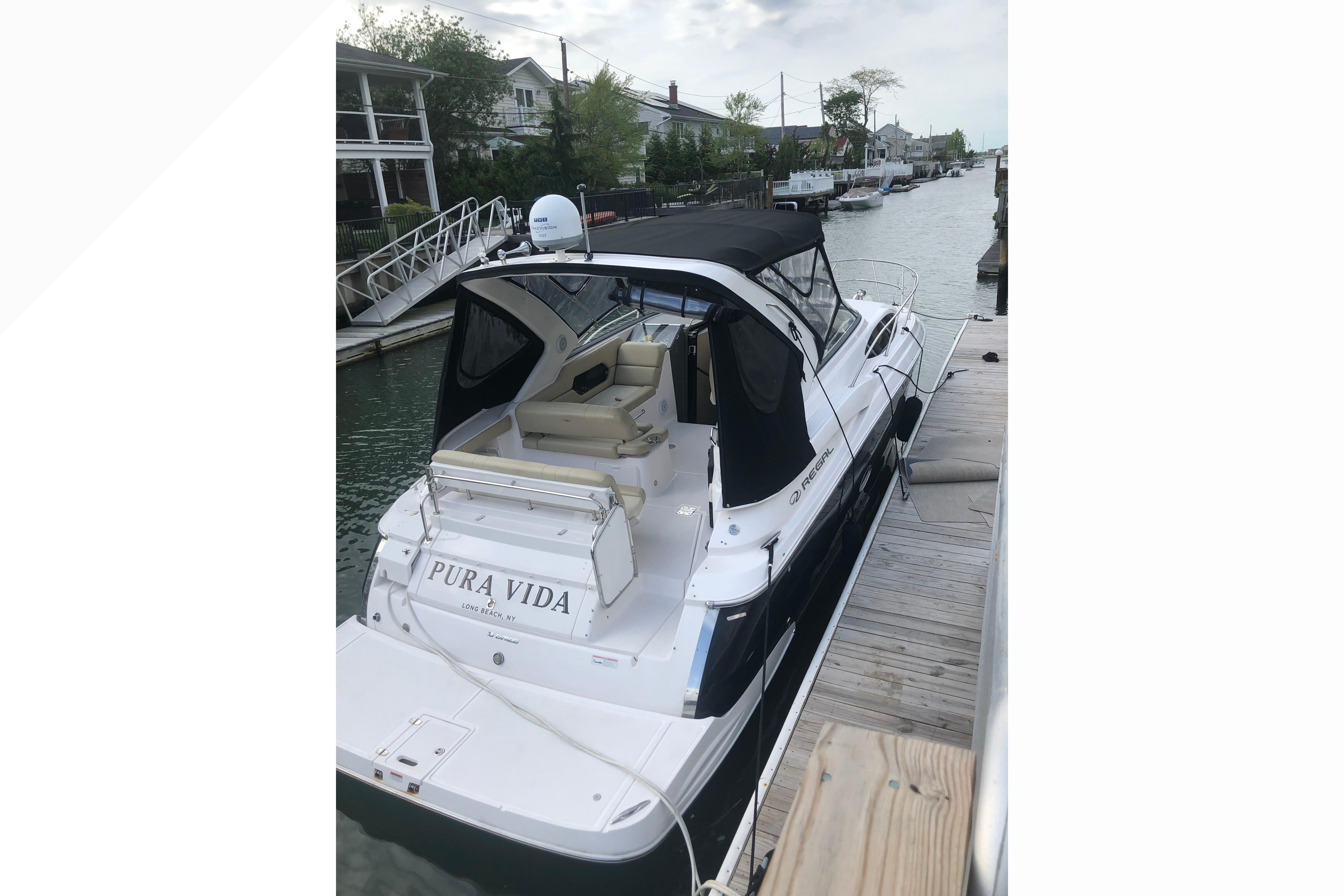 2012 Regal 35 Express Cruiser docked, featuring sleek design and black canopy.