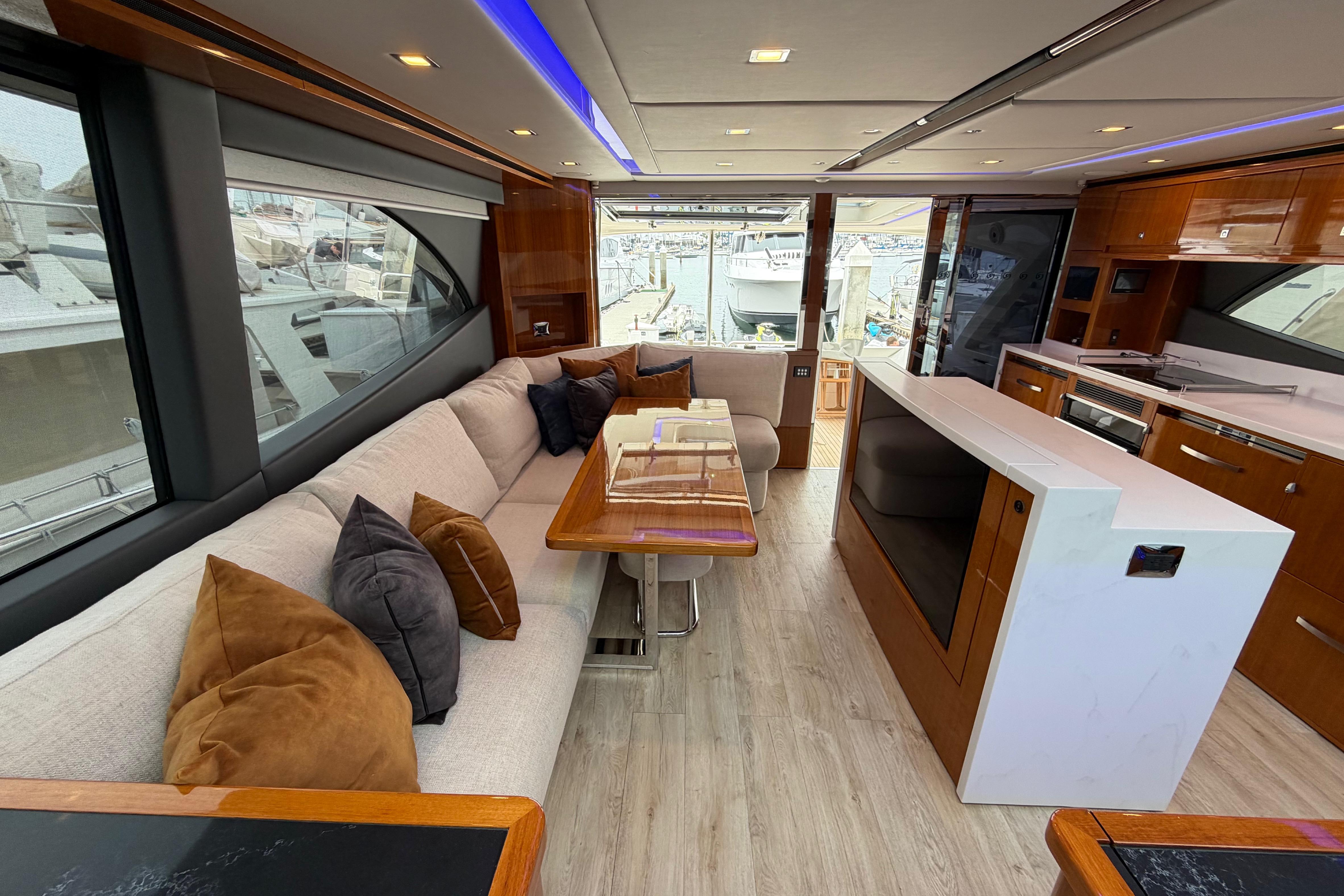 Luxurious interior of 2023 Riviera 645 SUV yacht with modern furnishings and large windows.