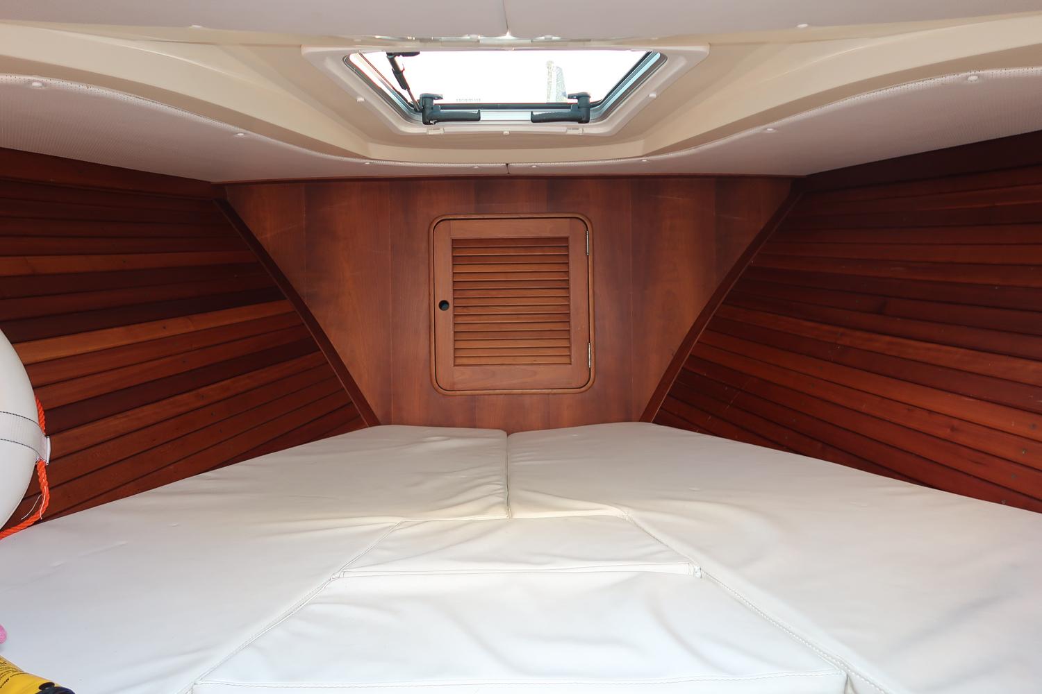 Interior cabin of 2004 Hinckley Talaria 29 Runabout with wood paneling and white cushions.