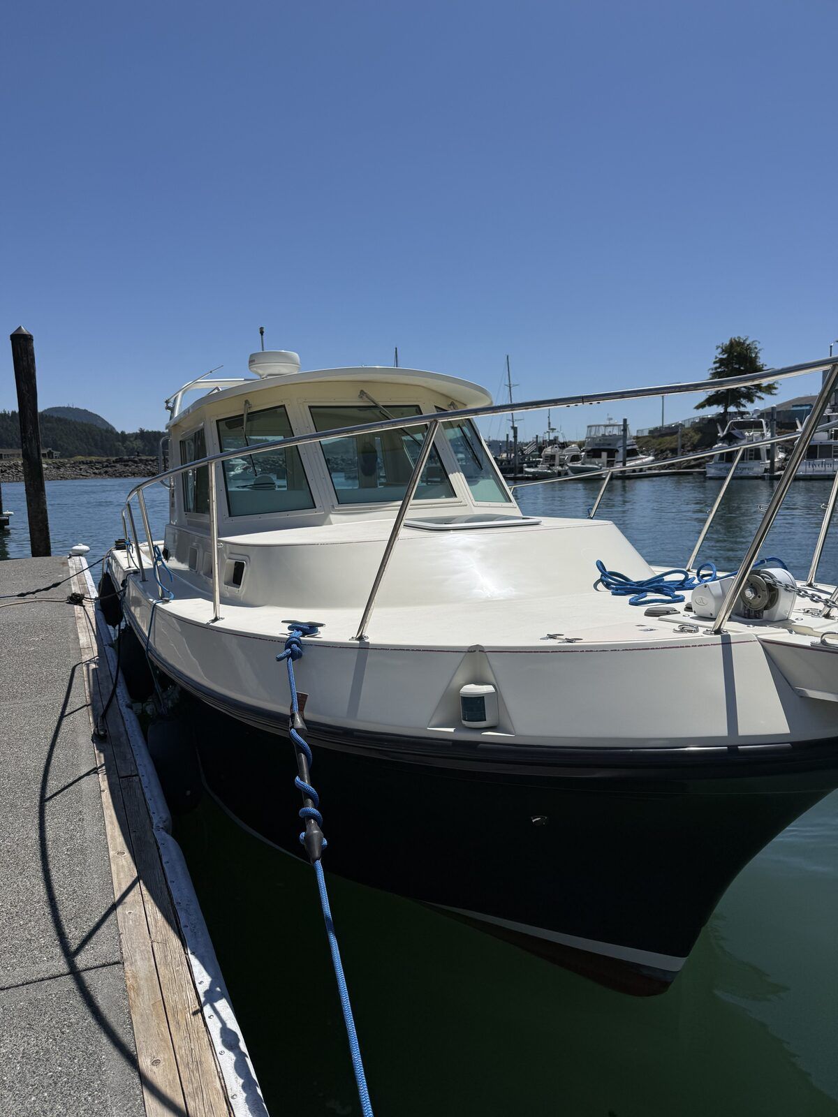 A white boat is docked, surrounded by calm water and a clear sky.