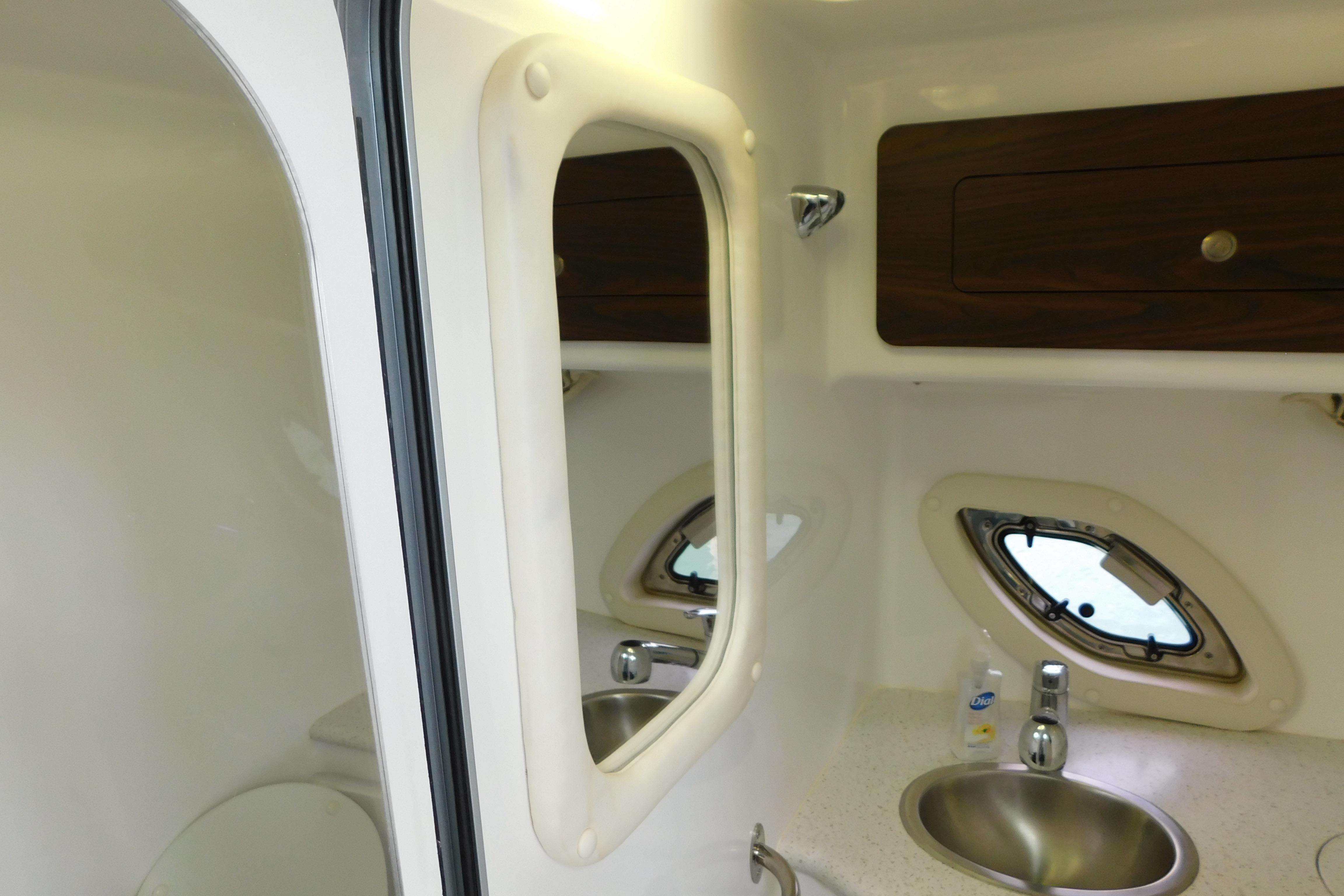 2017 Rinker EX 320 boat bathroom with sink, mirror, and porthole window.