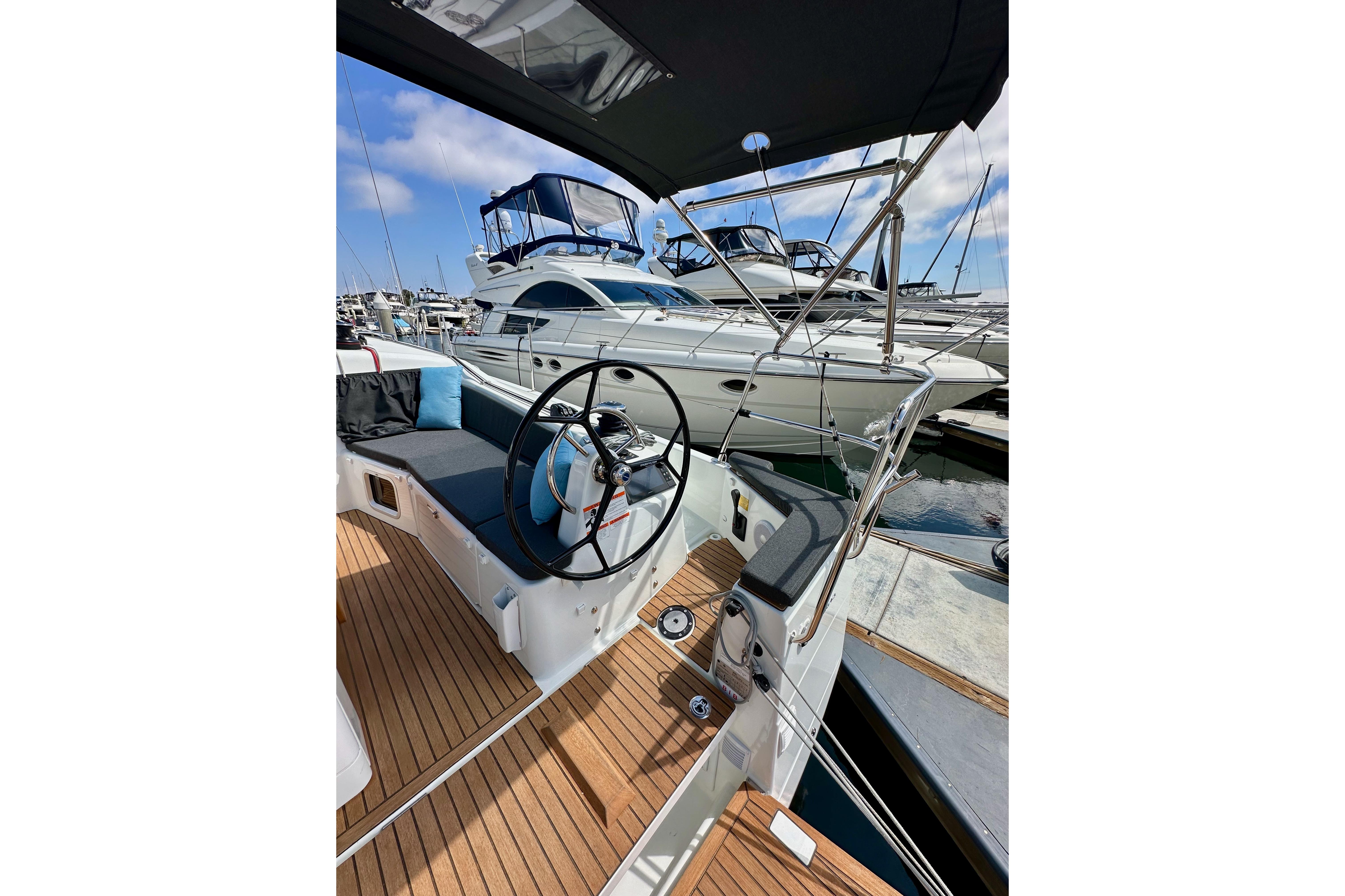 2024 Jeanneau Sun Odyssey 410 sailboat cockpit with steering wheel, docked at marina.
