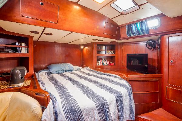 Luxurious cabin interior of a 1989 Concordia 52 yacht with a cozy bed and wooden finish.