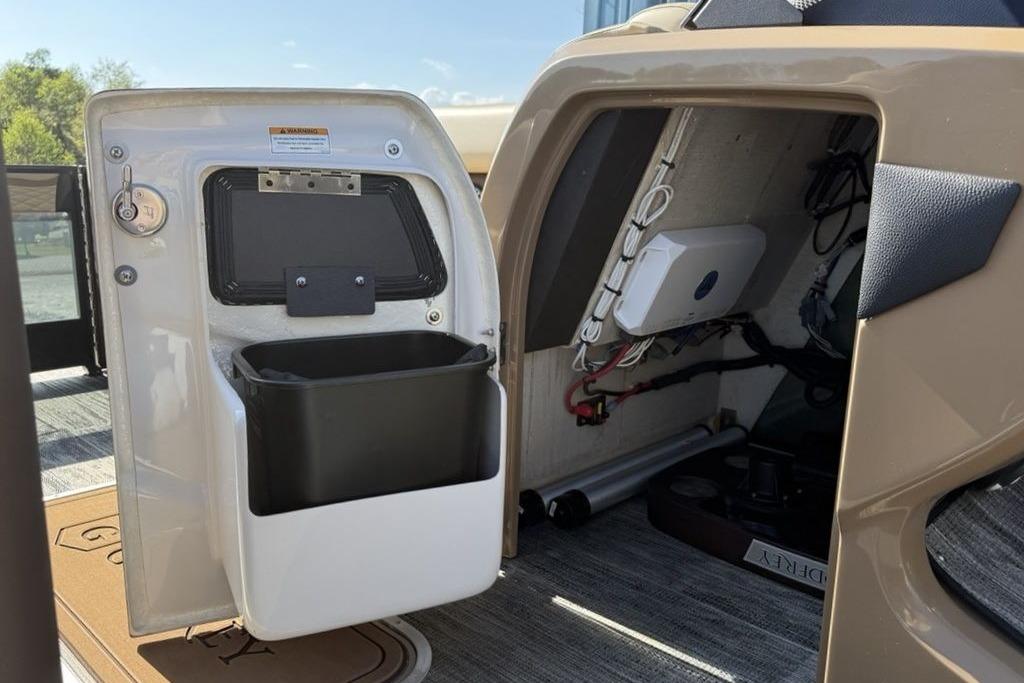 Interior view of 2026 Godfrey Monaco 235 SB boat storage compartment with wiring and storage bin.