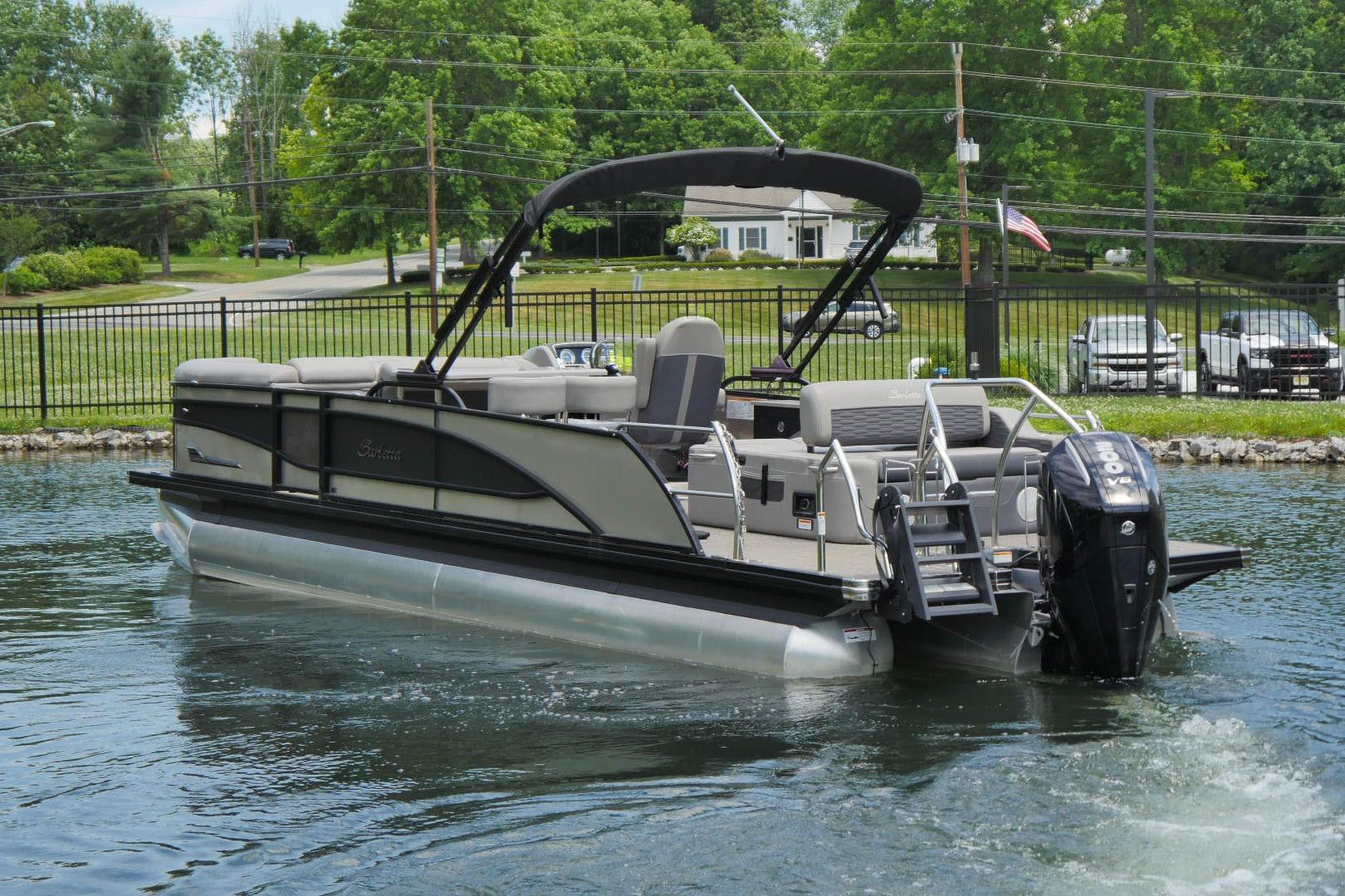 2023 Barletta CORSA 25UE pontoon boat on water, surrounded by greenery.