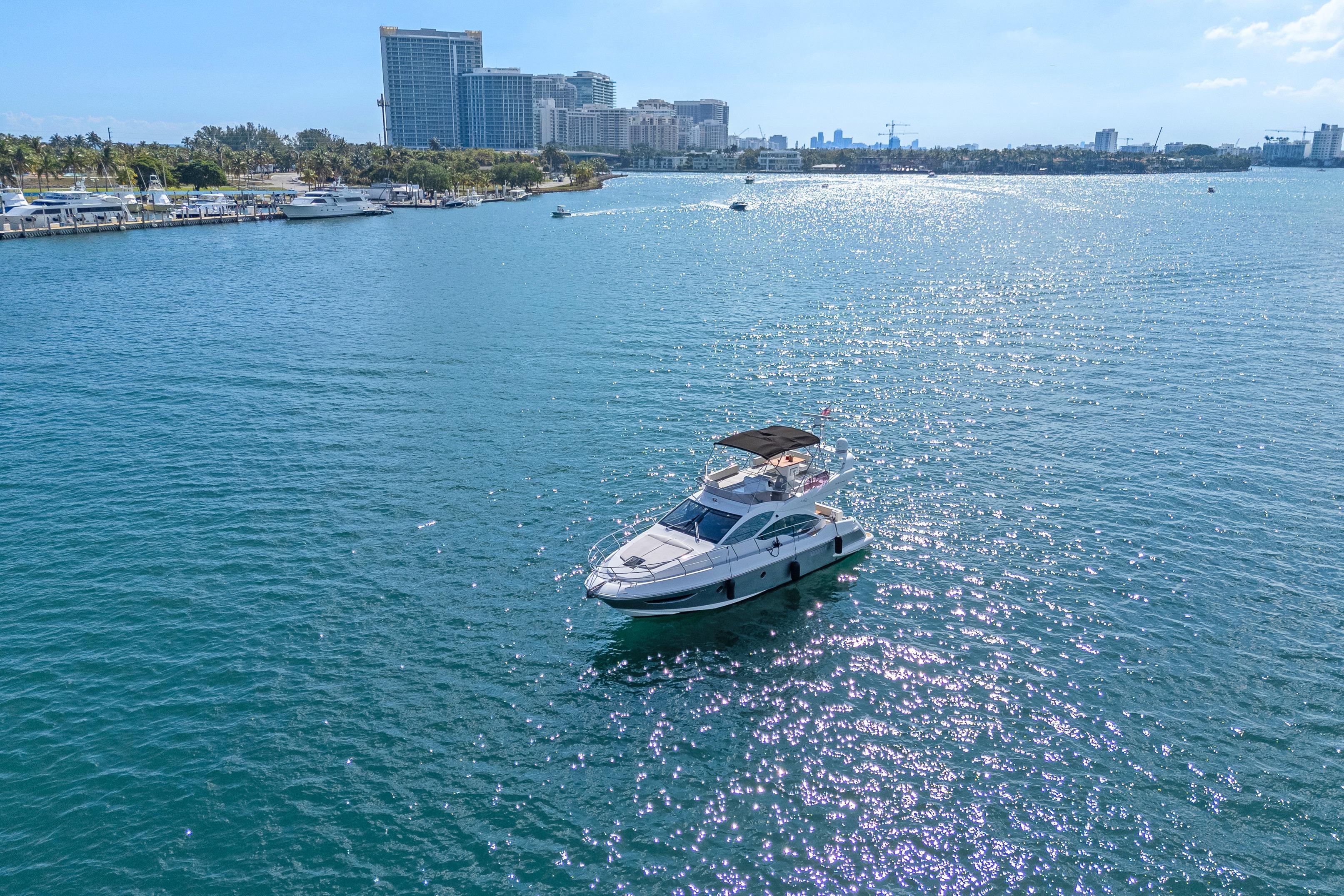 Azimut 45 Flybridge 2013 yacht cruising on a sunny day near city skyline.