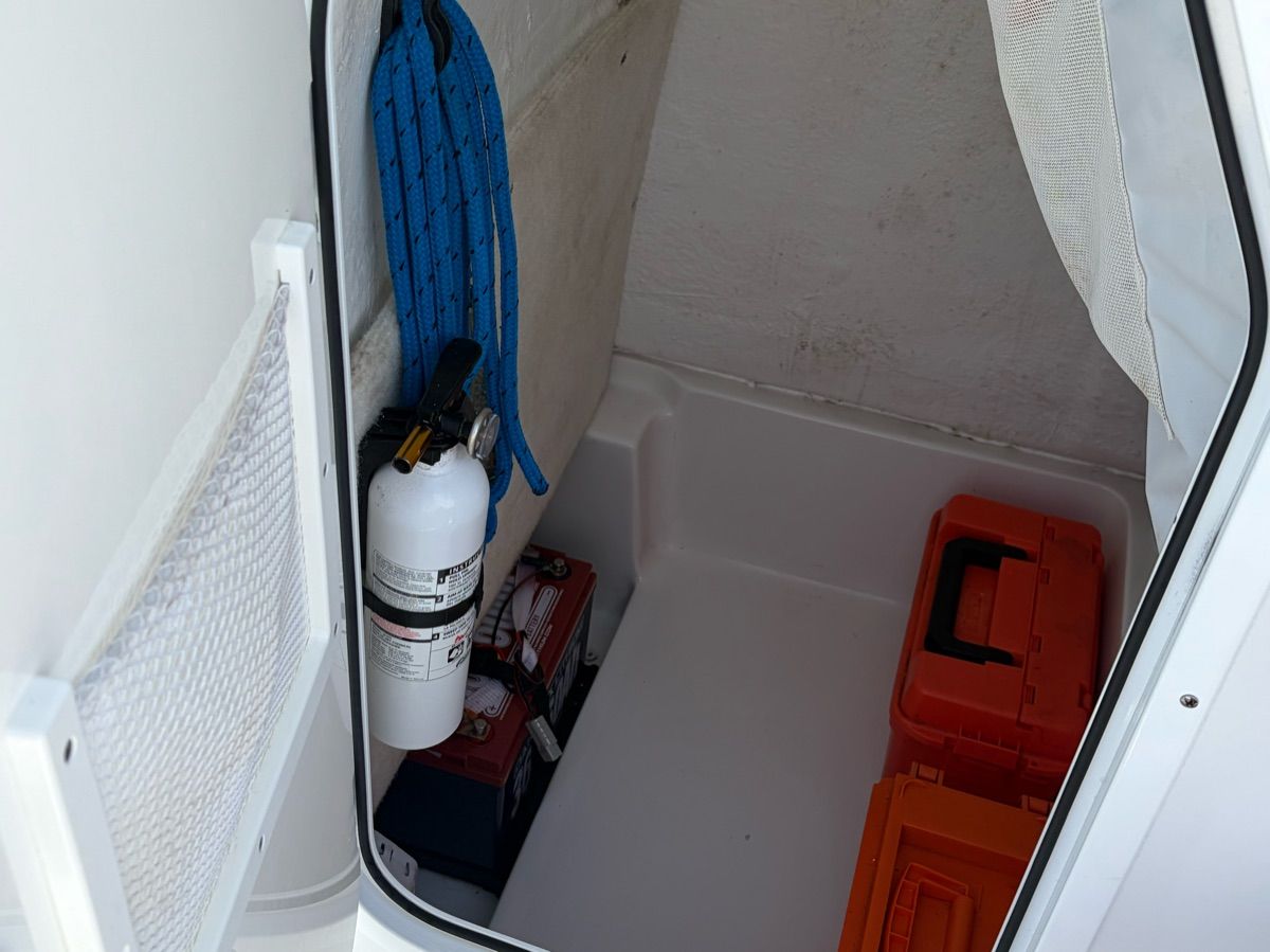 Storage area with fire extinguisher, blue rope coil, and orange boxes.