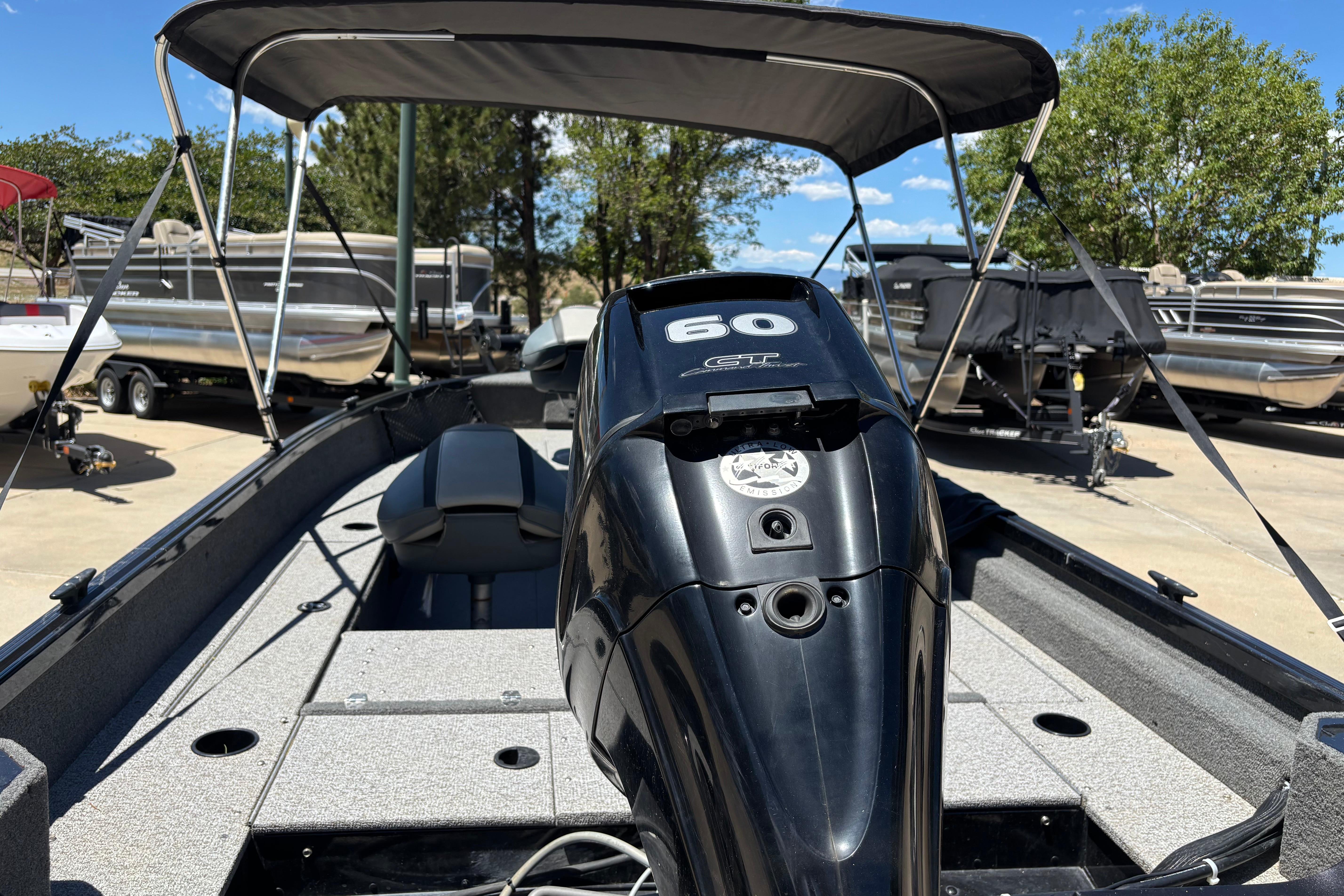 2021 Alumacraft Classic 165 boat with 60 HP engine, parked outdoors under a canopy.
