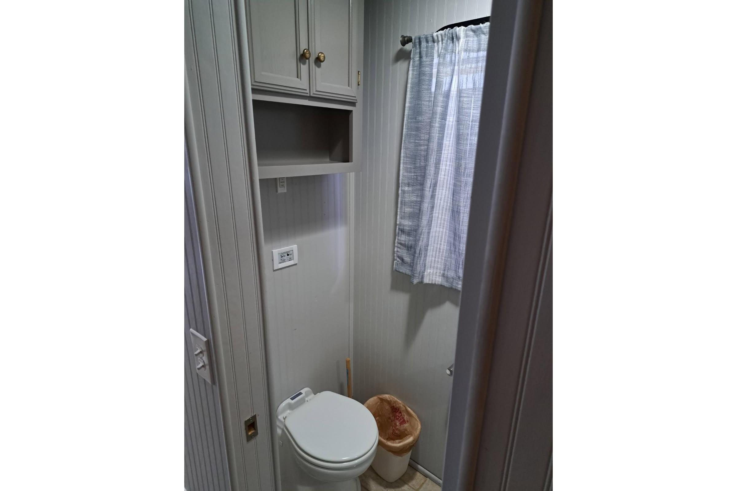 Compact bathroom in a 1990 Sumerset 16 x 70 houseboat, featuring a toilet and storage cabinet.