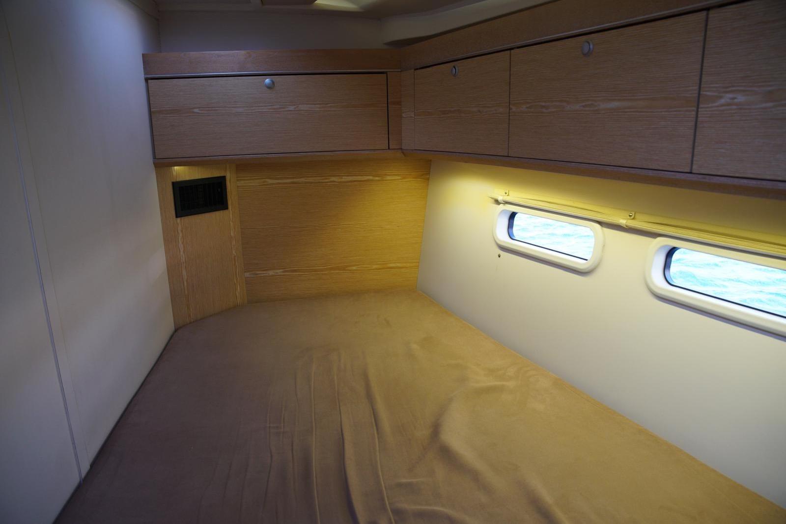 Interior cabin of 2013 Hanse 575 yacht with wooden cabinetry and porthole windows.