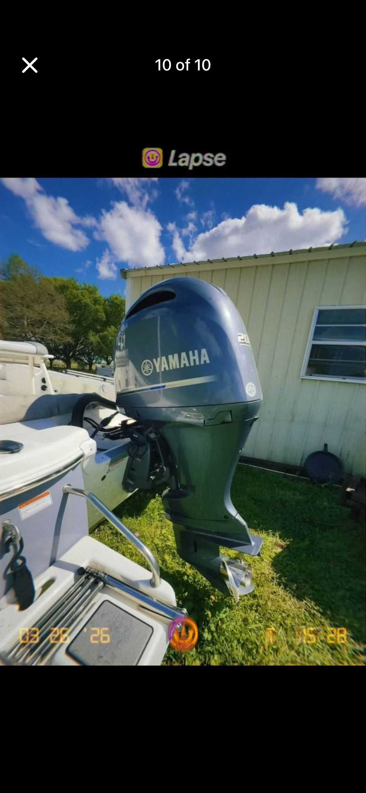 A Yamaha outboard motor is attached to a boat on a lawn next to a building.