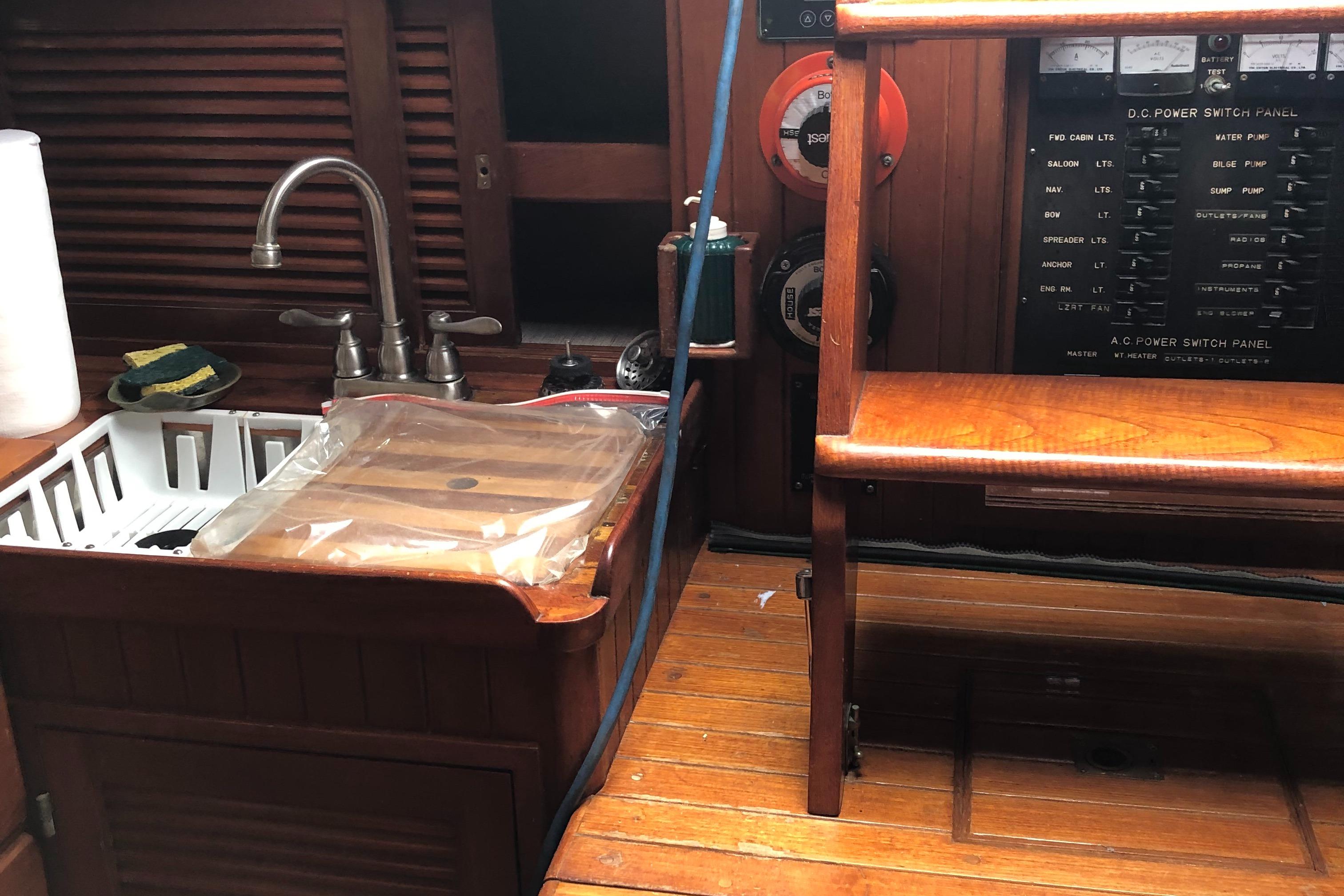 Interior of 1985 Tayana 37 sailboat with wooden cabinetry and sink area.