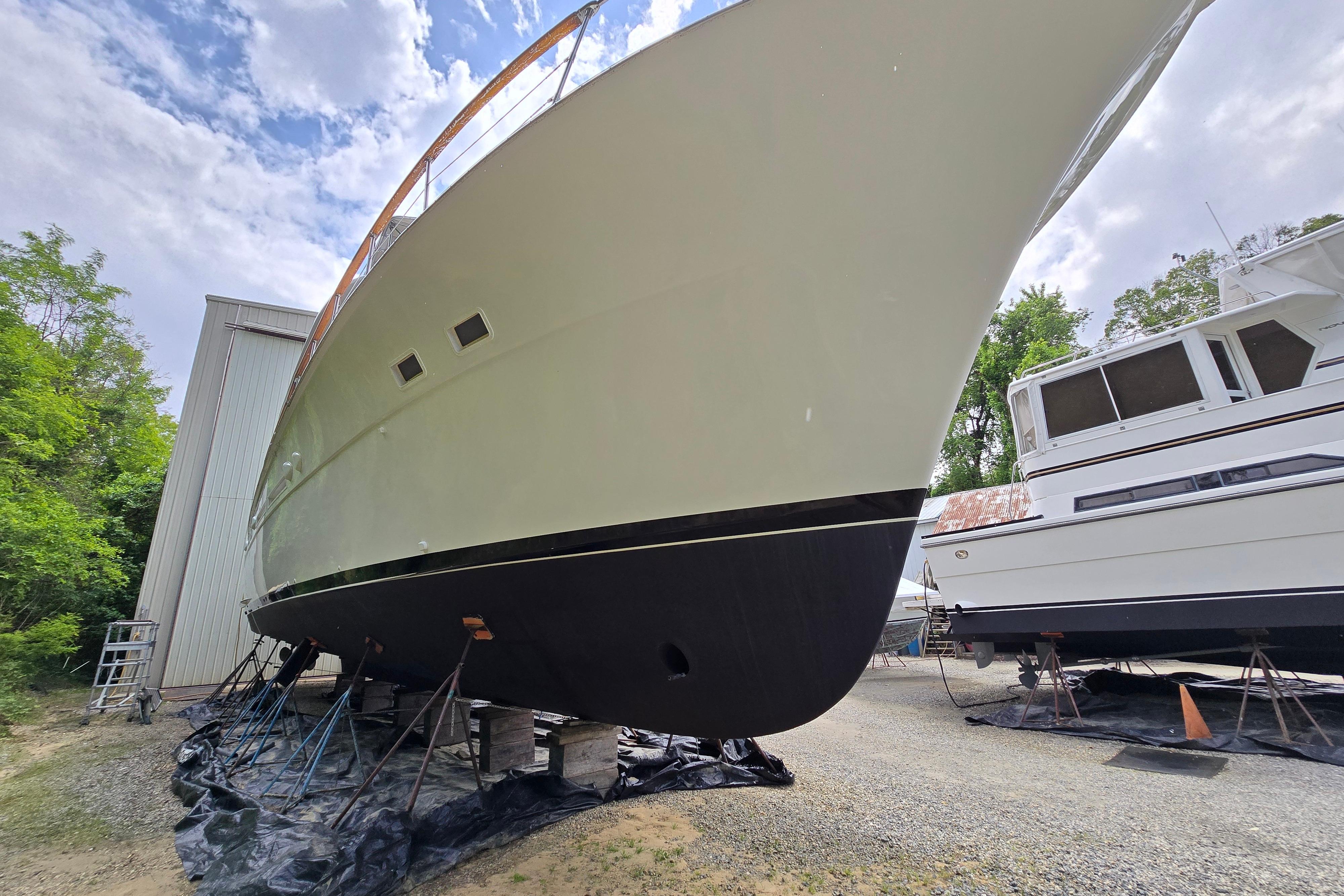 1980 Hatteras 70 Motor Yacht on dry dock, side view under cloudy sky.