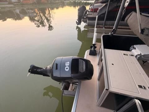 An outboard motor on a boat in calm water at sunset.