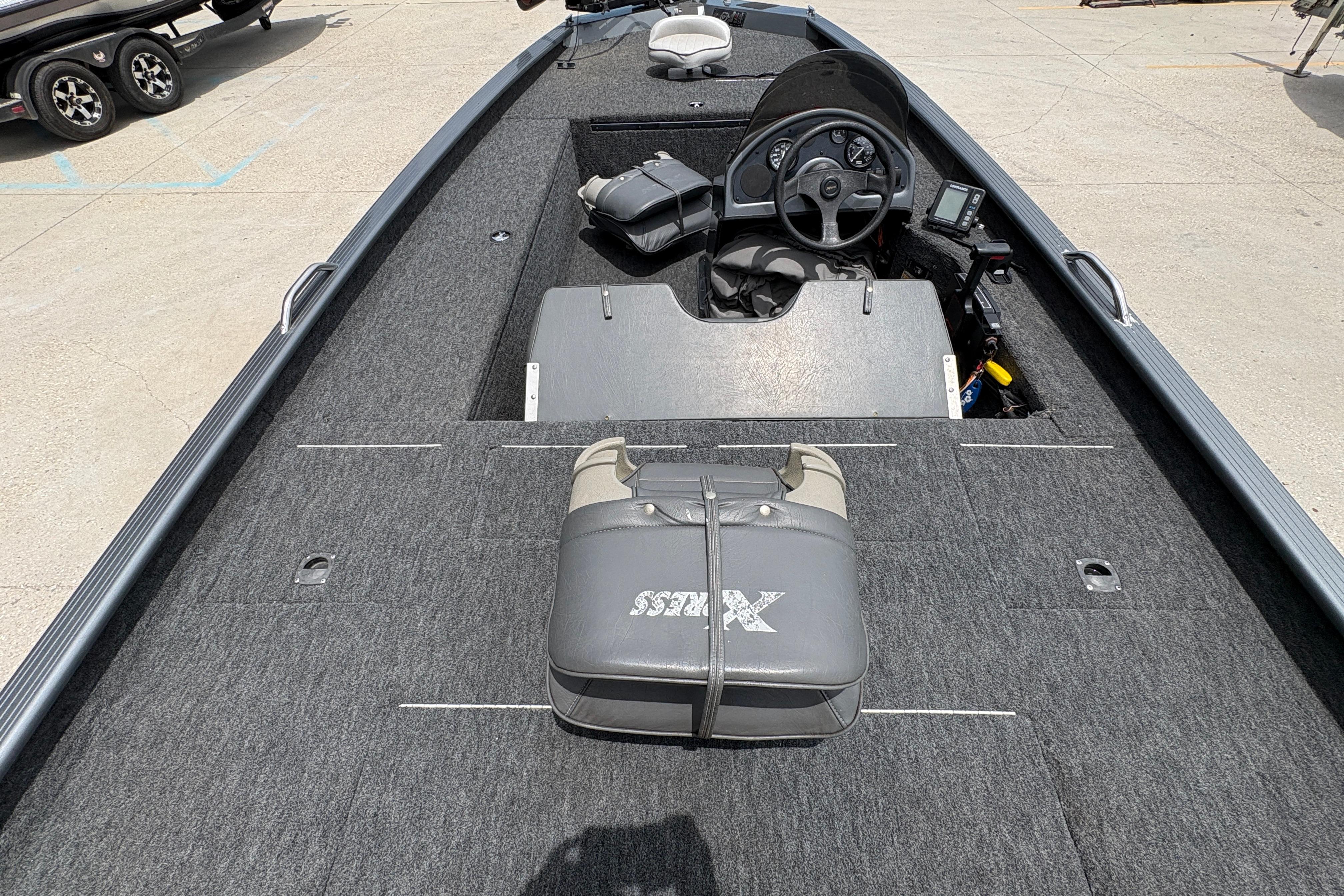 2000 Xpress X18 boat interior with steering console and seating on a concrete surface.