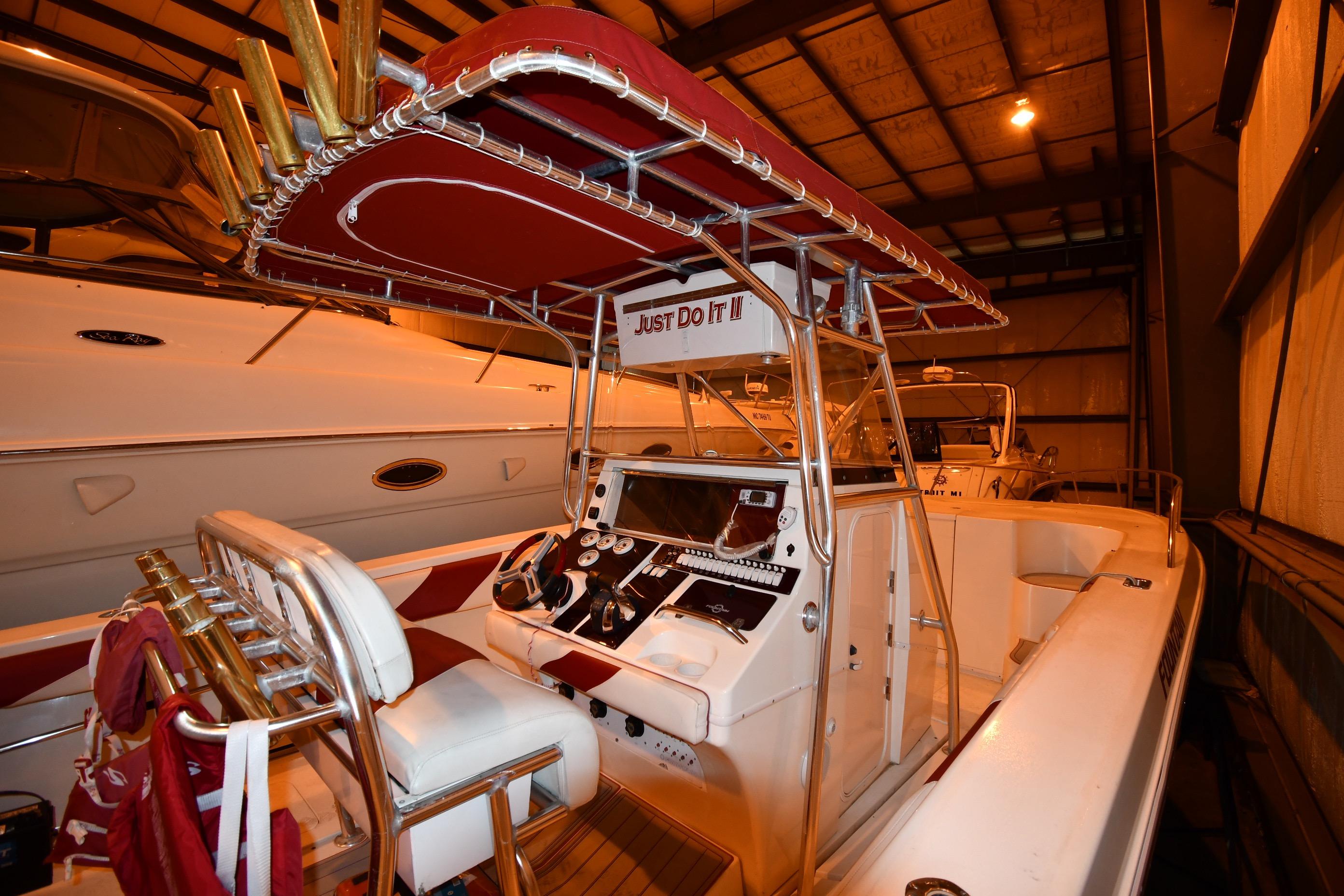 2001 Fountain 38 Center Console boat in storage, featuring red canopy and fishing rod holders.