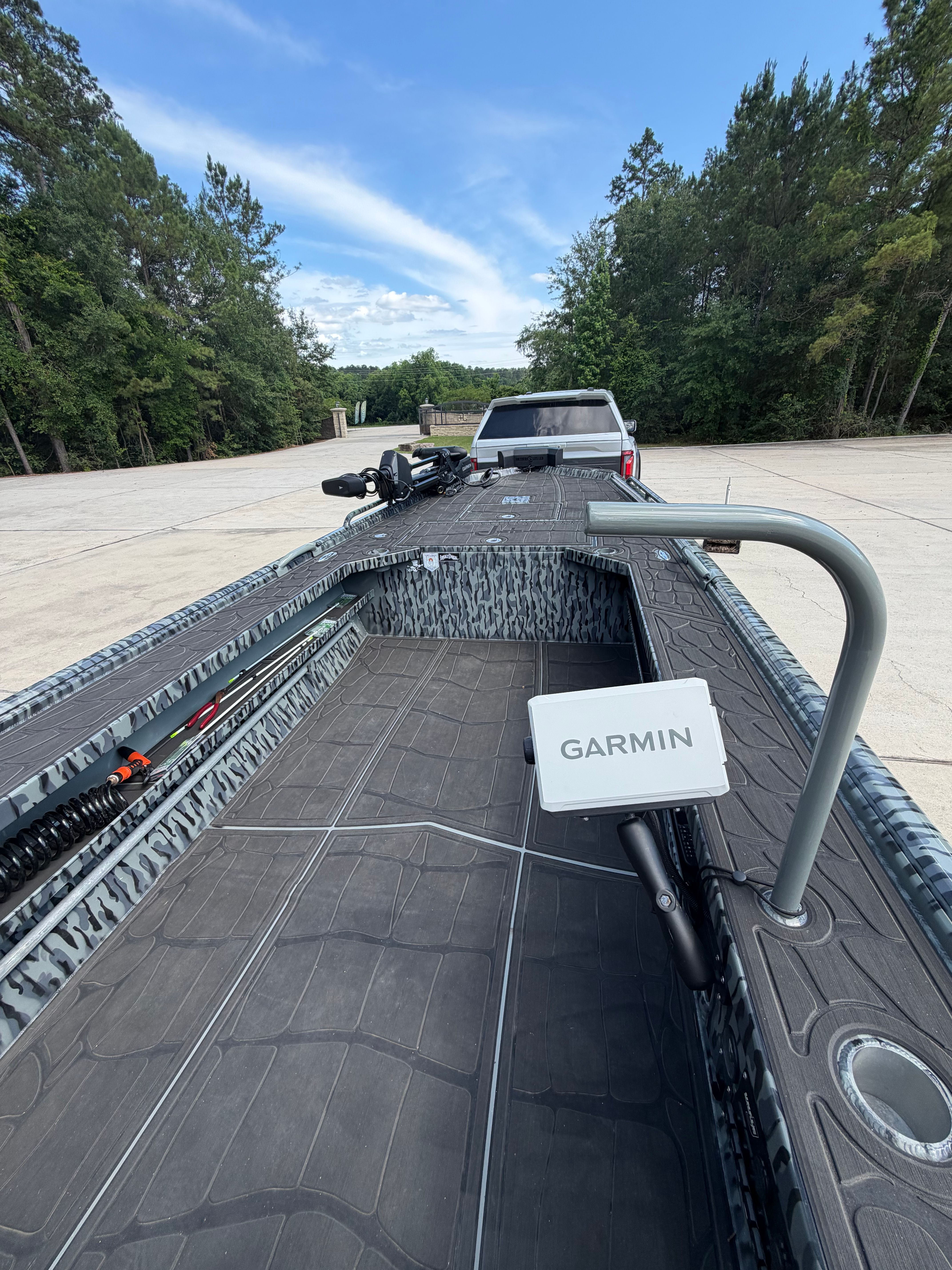A modern boat with Garmin technology on a trailer, surrounded by trees.