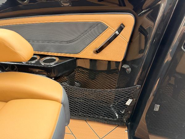 2025 Yamaha Boats 255XD interior with tan and black seating, cup holders, and storage net.