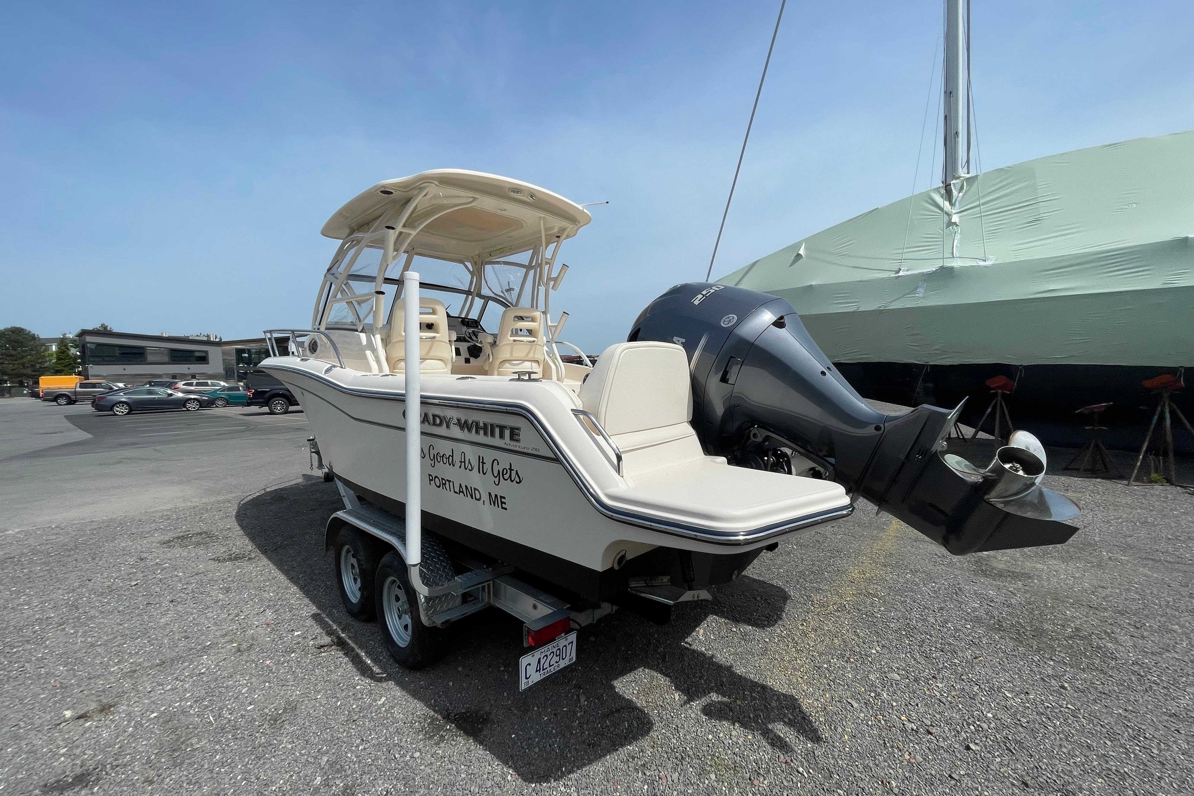 2024 Grady-White Adventure 218 boat on trailer, parked outdoors, featuring powerful outboard motor.