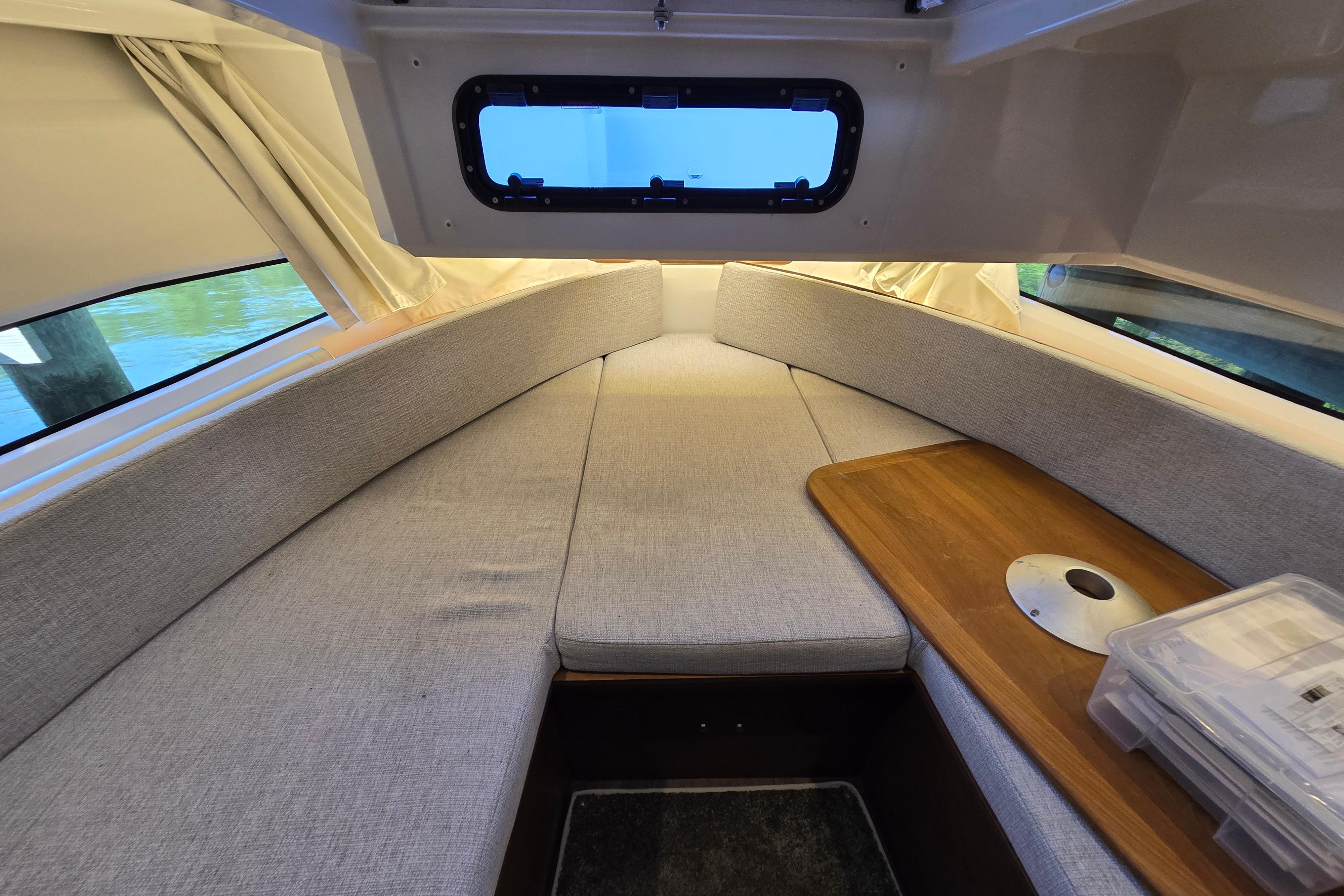 Interior of the Jeanneau NC Sport 895 with gray cushions and a wooden table.
