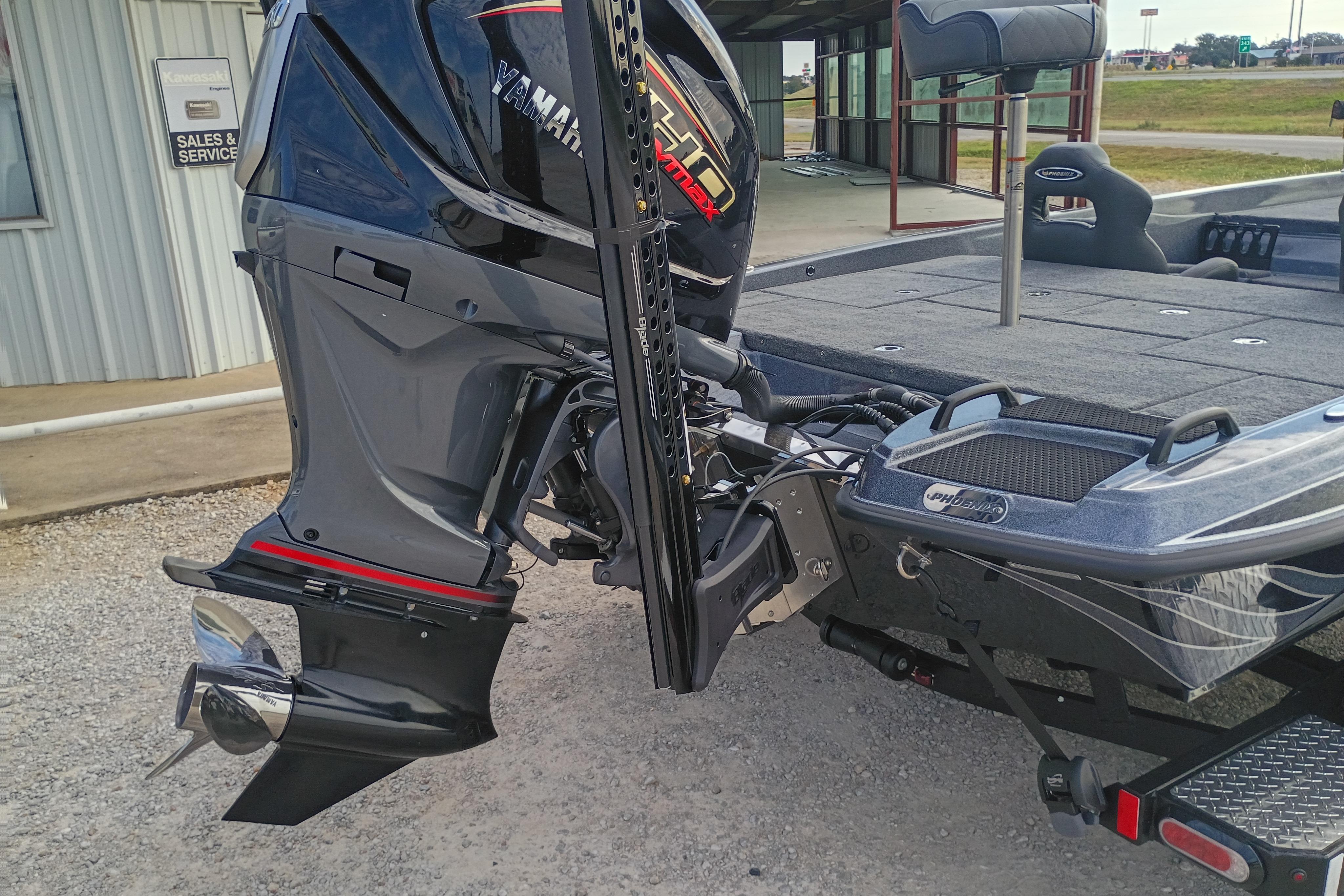 2026 Phoenix 921 ELITEX boat with Yamaha outboard motor, parked near sales and service building.
