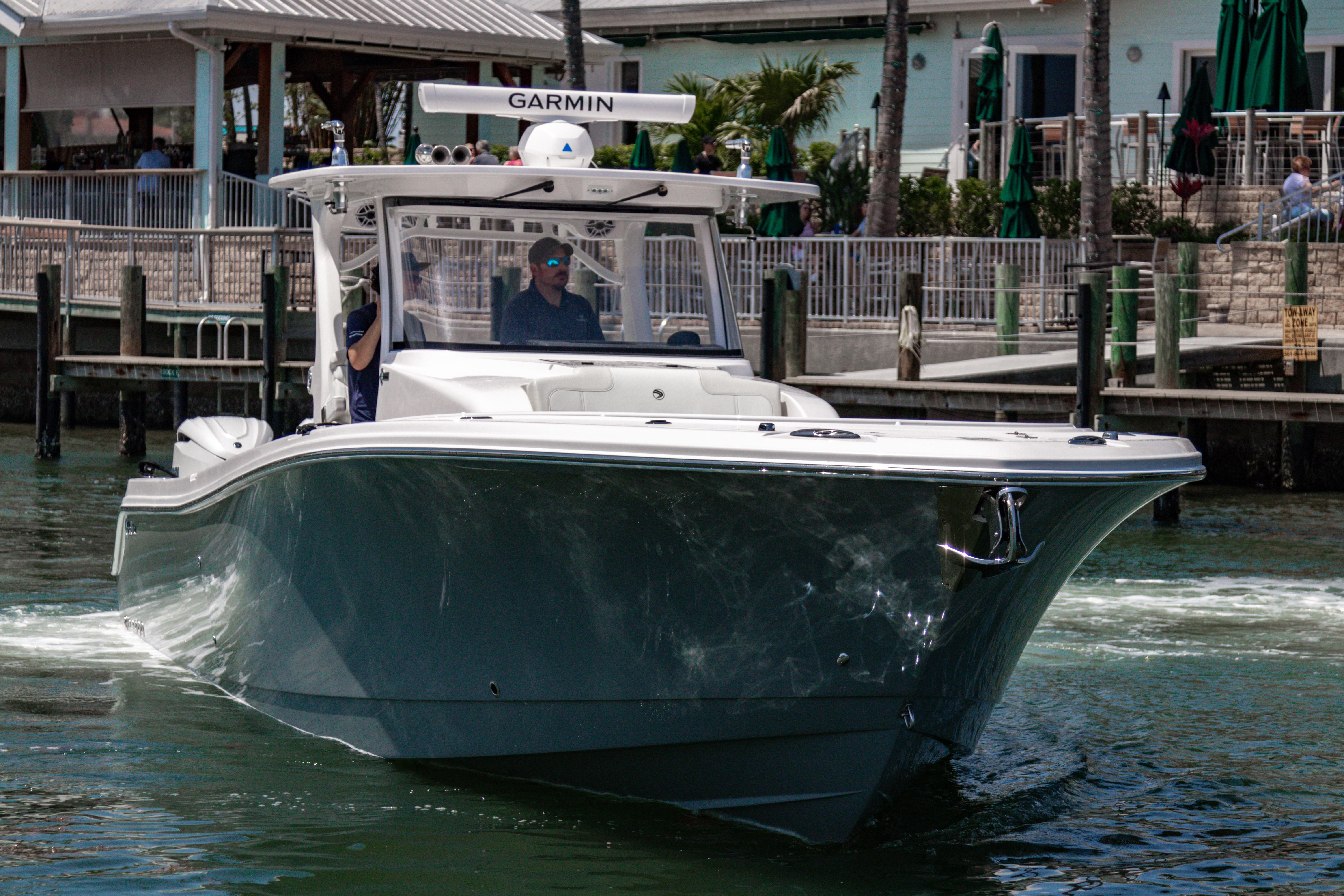 2025 Edgewater 370CC boat cruising near a dockside restaurant.