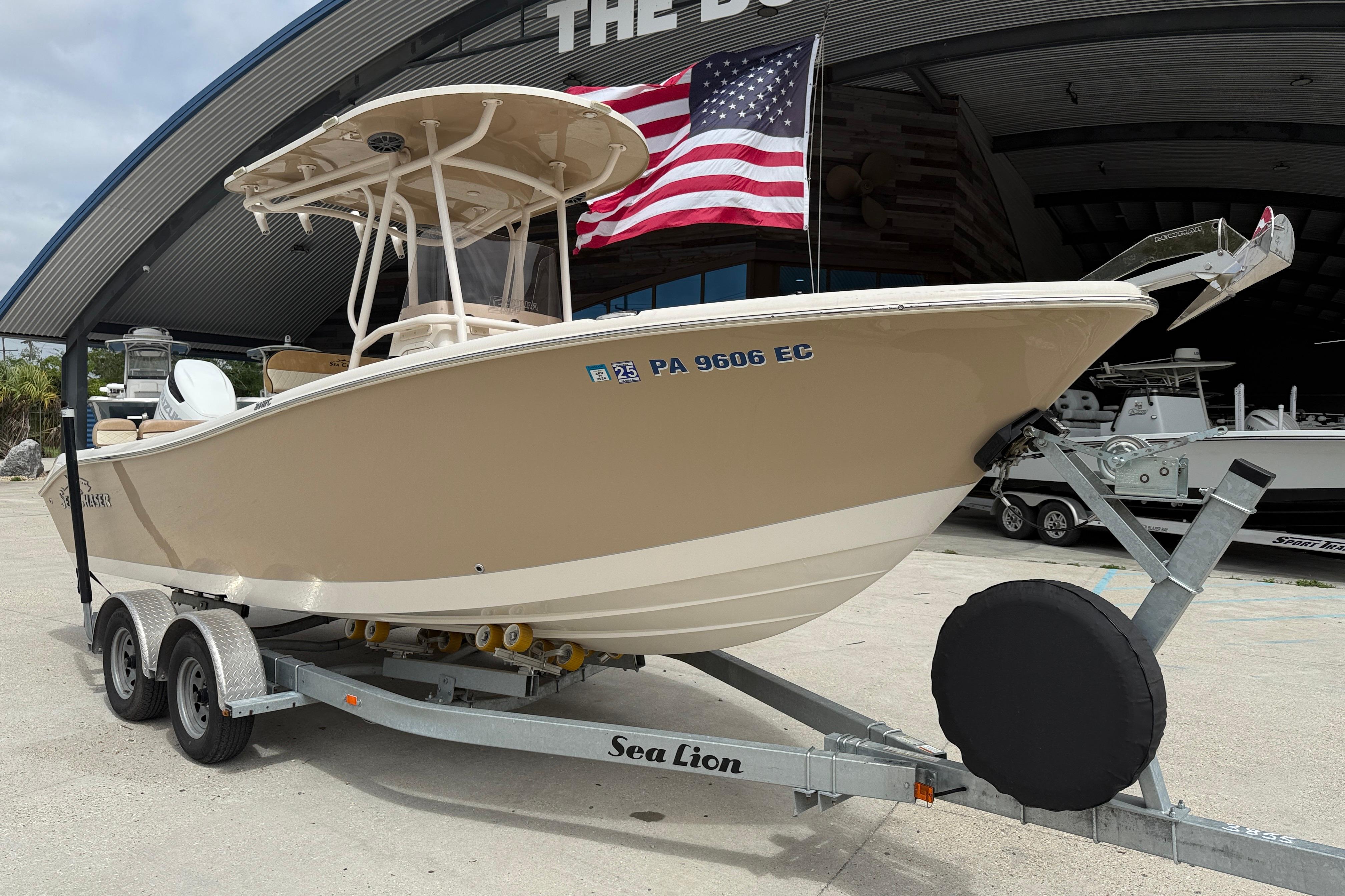 2023 SeaChaser 24 HFC boat on trailer, American flag in background.