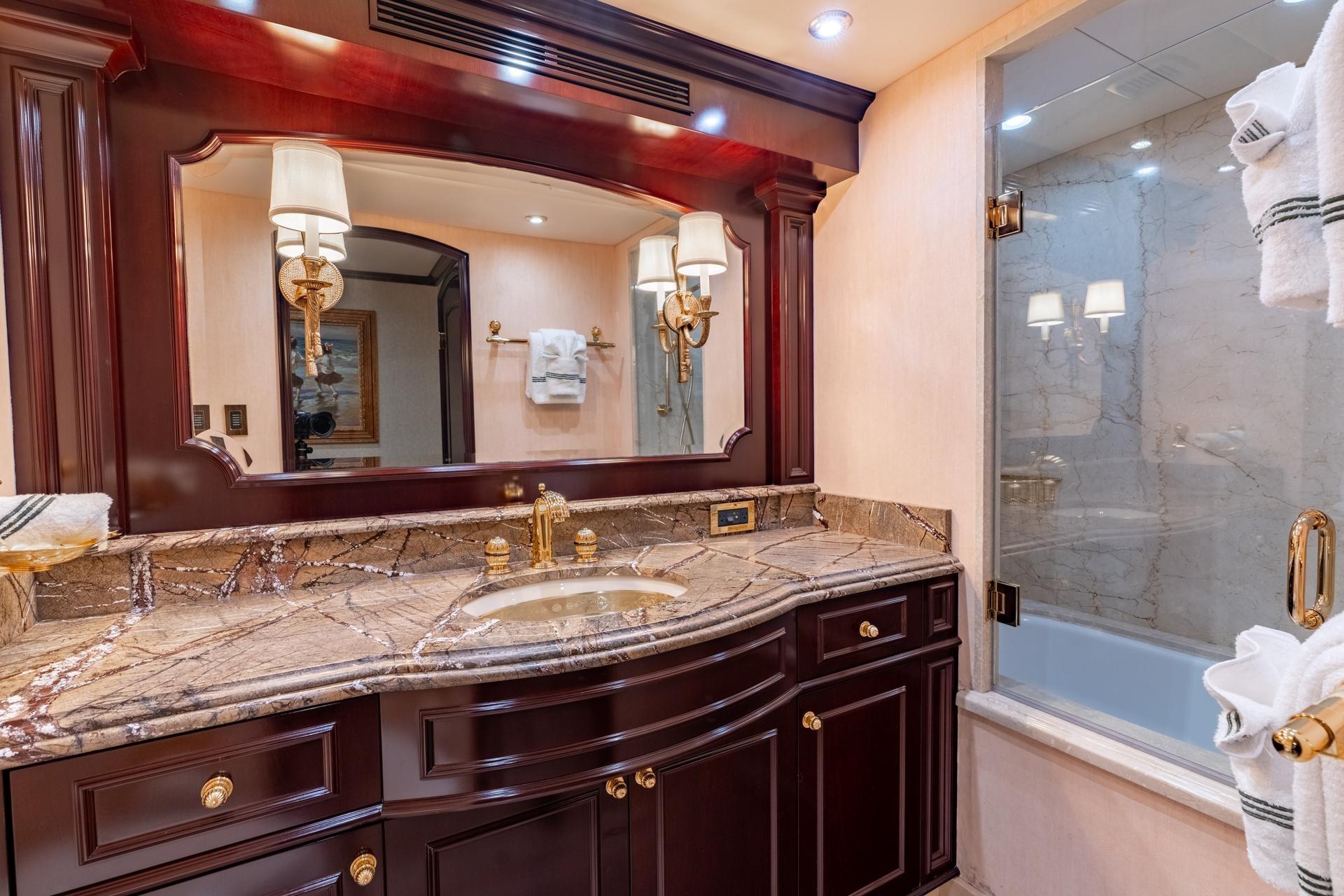 Luxurious yacht bathroom with marble countertop and elegant wooden cabinetry, Trinity Tri-Deck Motor Yacht 2006.