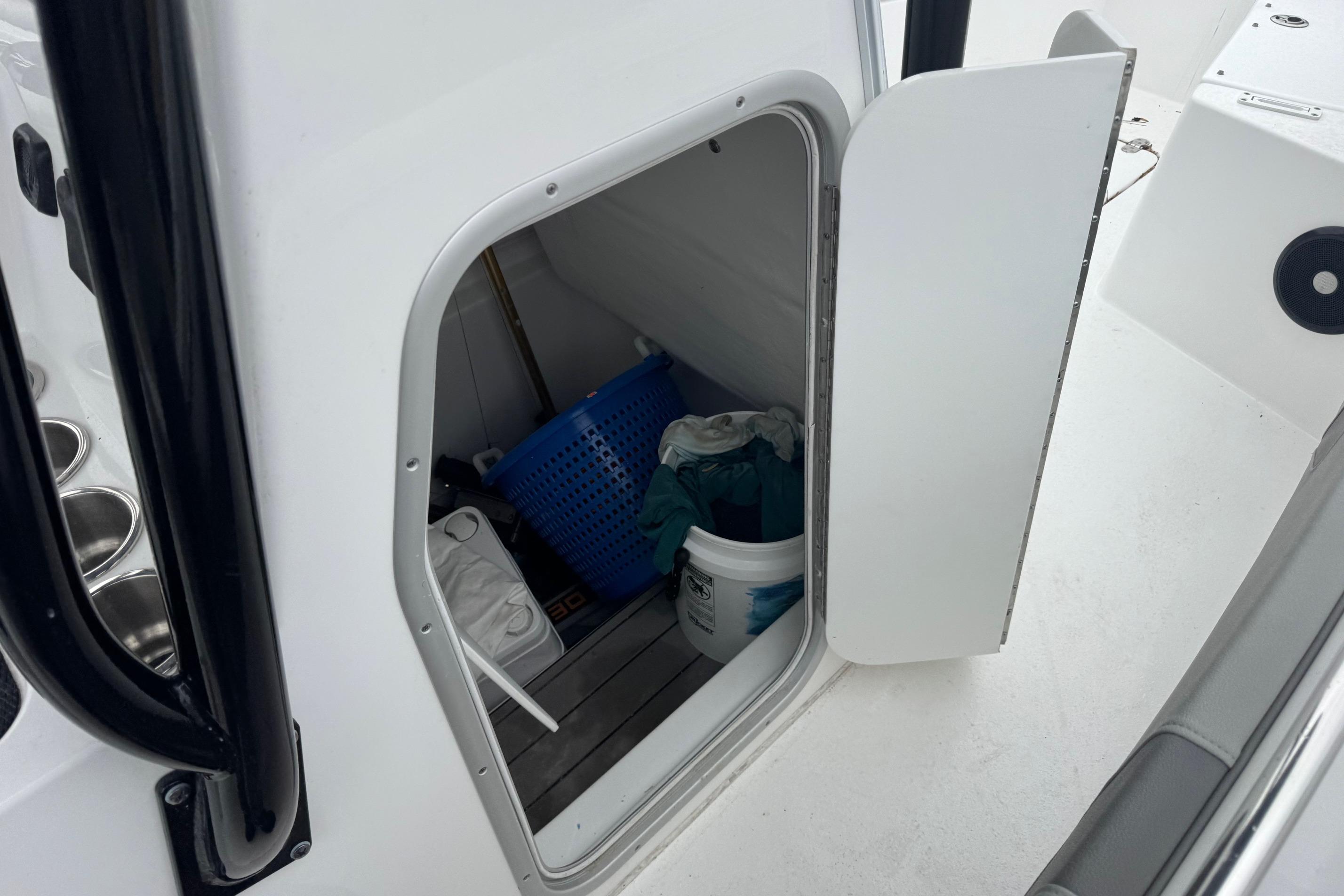 Storage compartment on 2024 Cape Horn 32 XS boat, containing cleaning supplies and a basket.