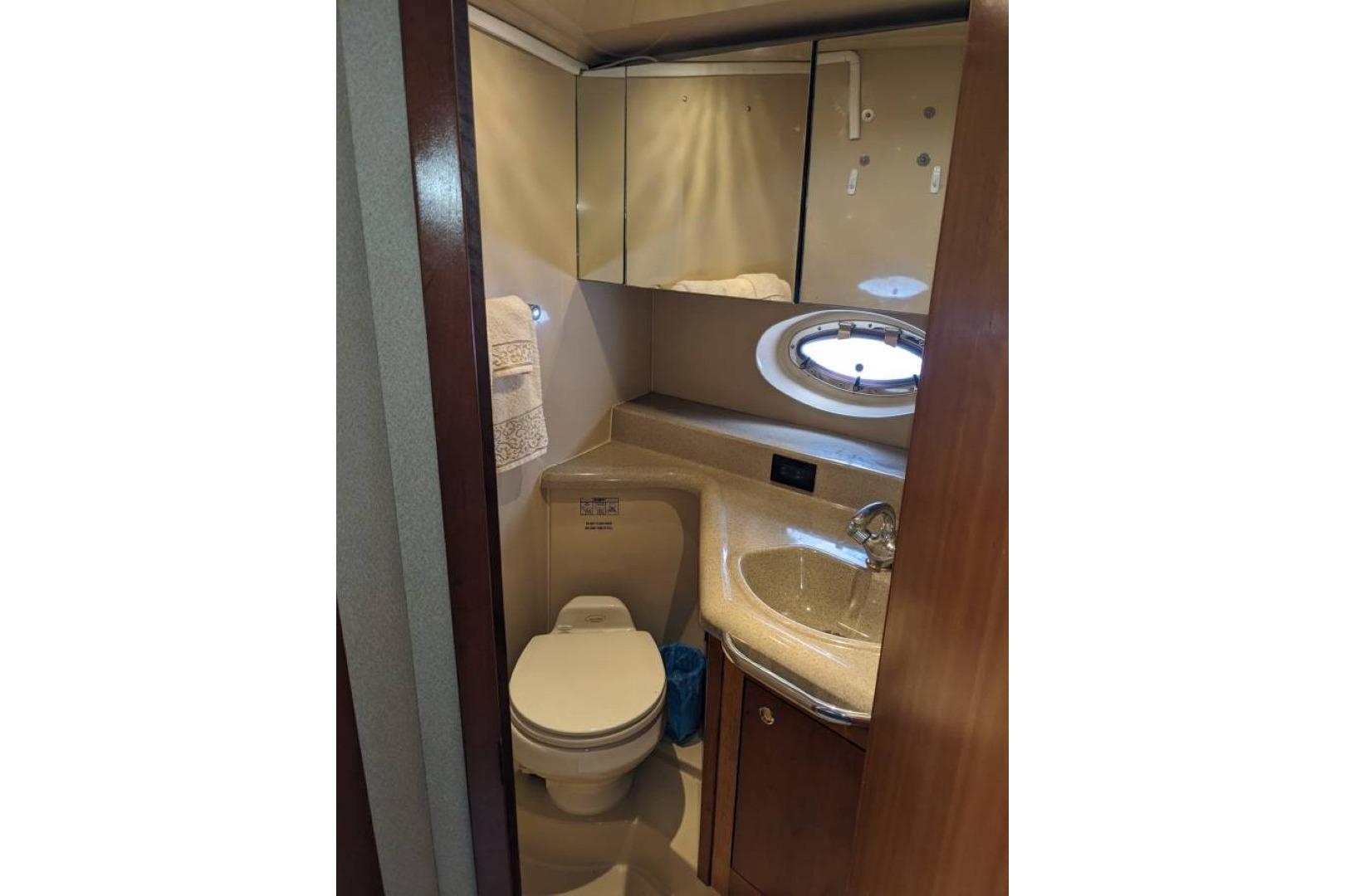 Compact bathroom in 2003 Cruisers 3970 yacht with sink, toilet, and mirrored cabinet.