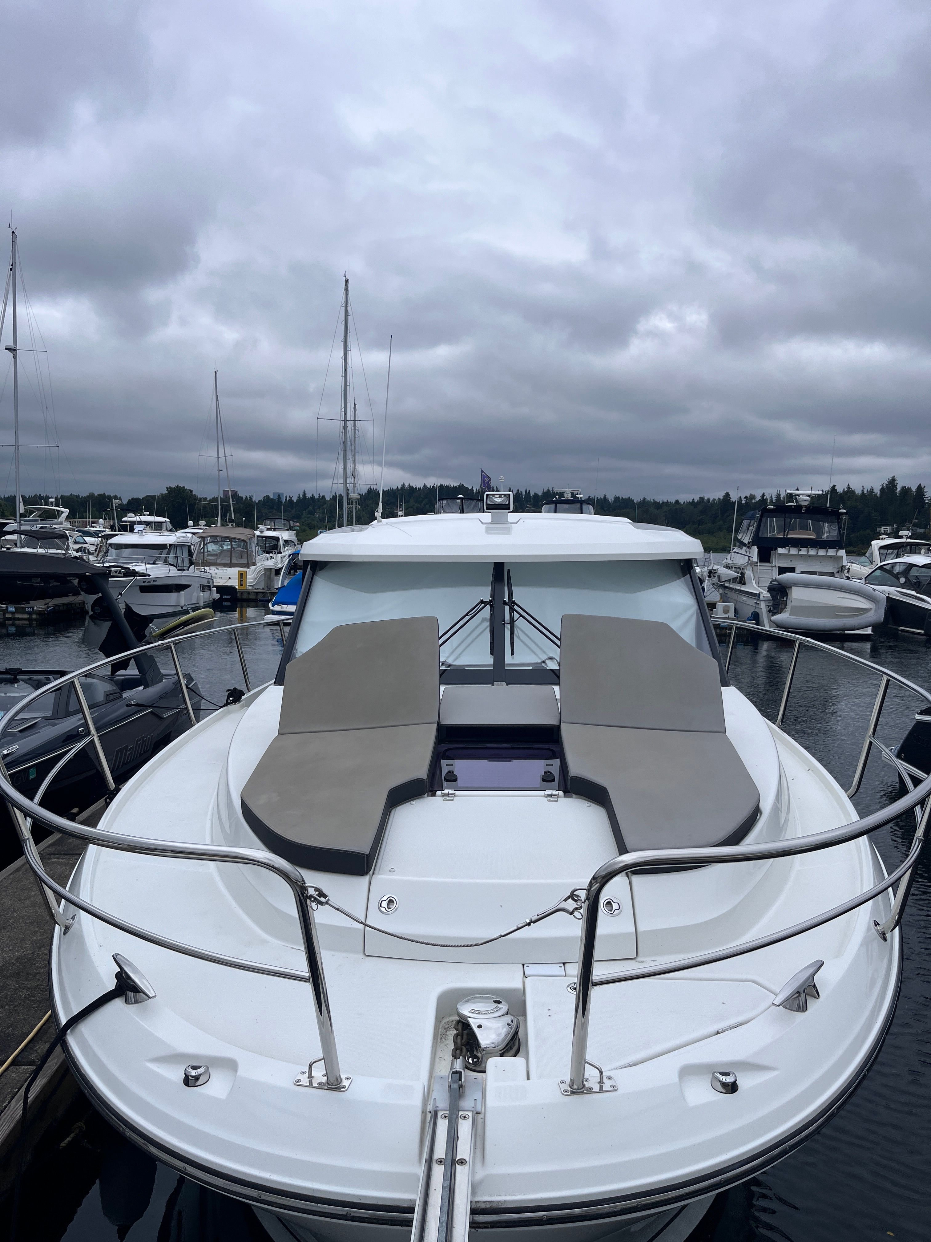 A 2021 Jeanneau NC 1095 docked in a marina. It features a spacious foredeck with seating.
