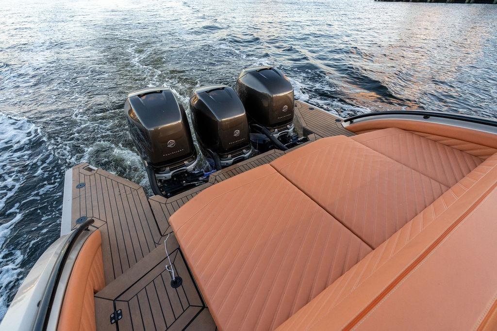 2023 DeKoning 43 boat with triple outboard engines and luxurious tan seating on water.
