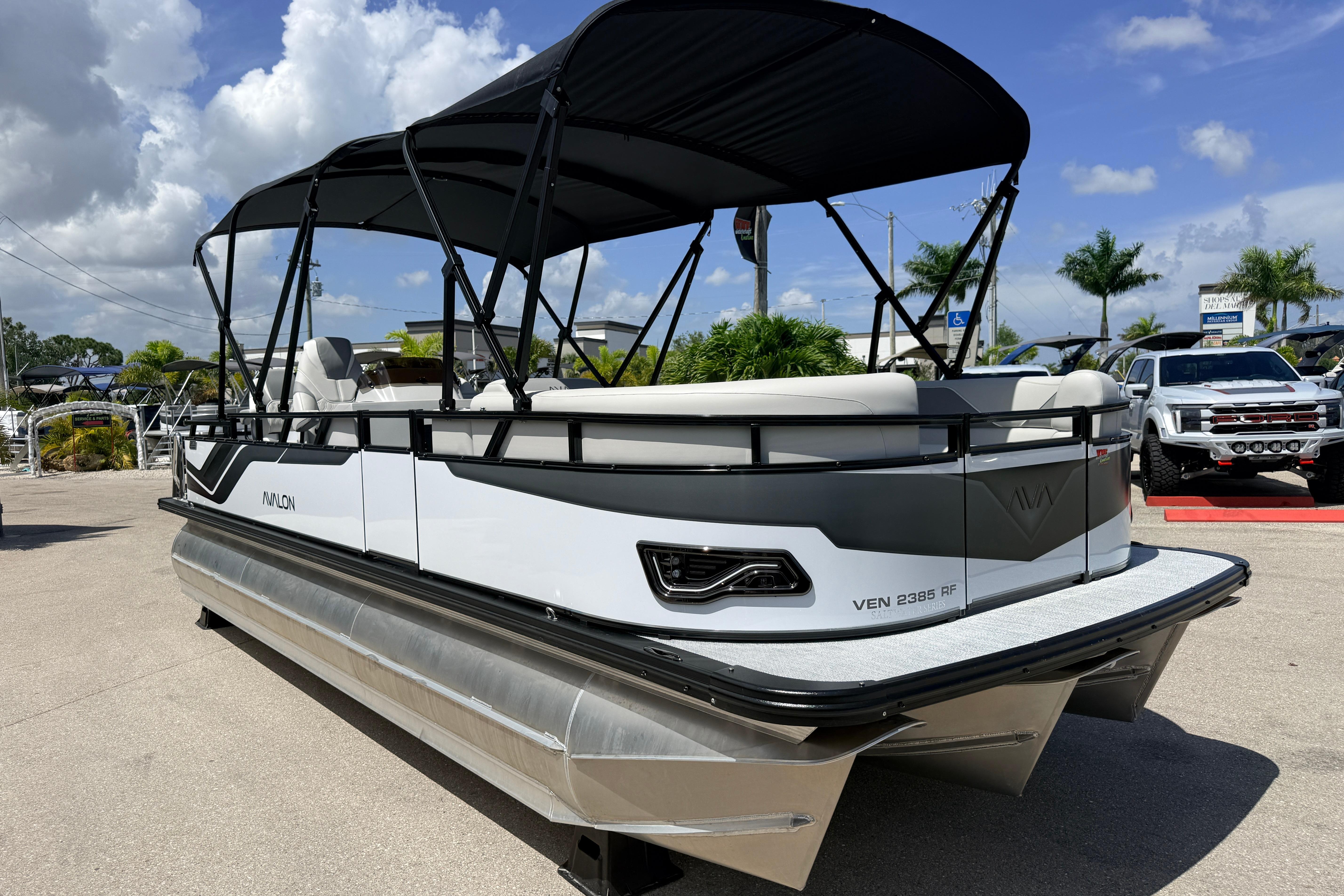 2026 Avalon 2385 Venture Tri Toon boat with canopy, parked outdoors under a cloudy sky.