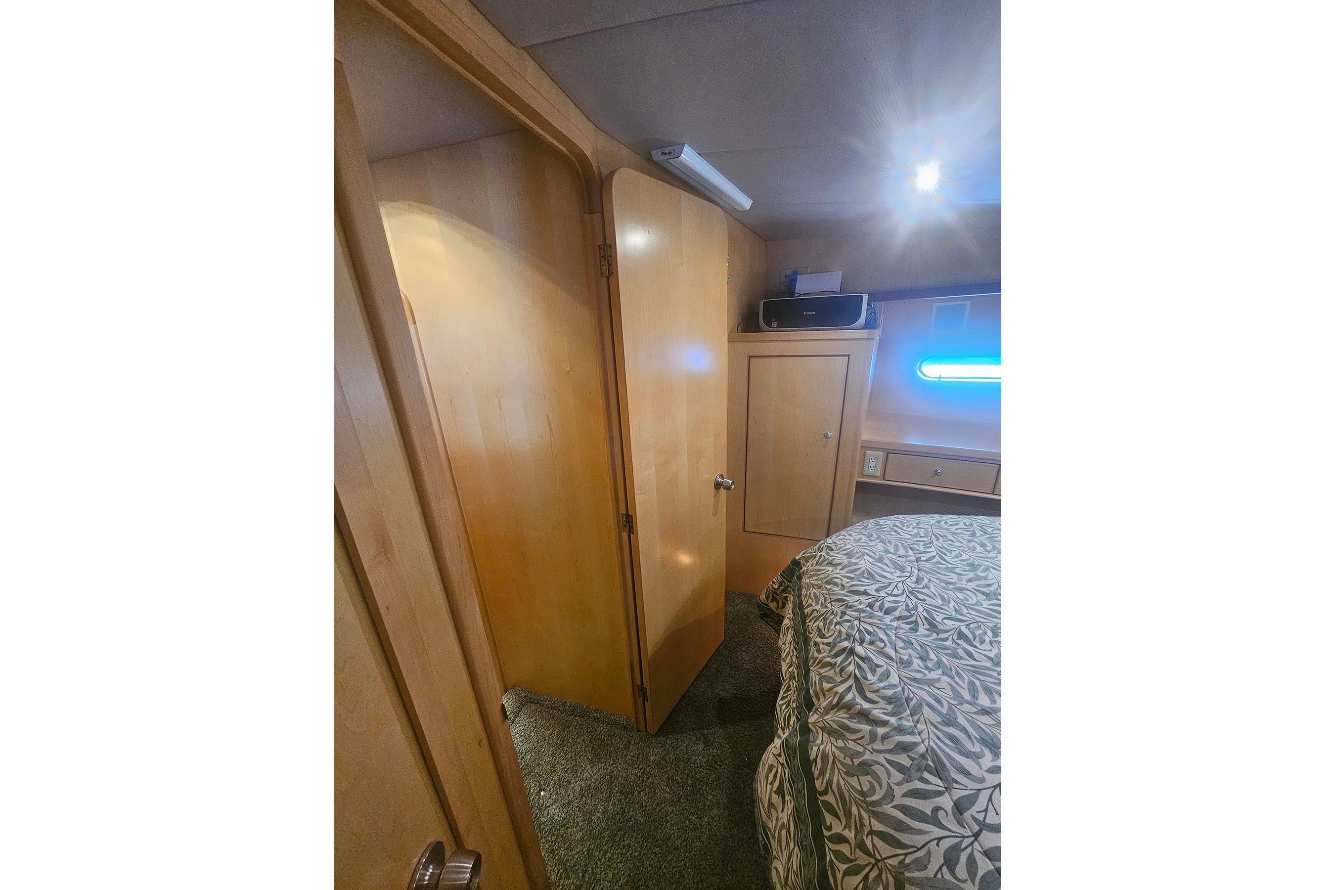 Interior of a 1995 Symbol 55 yacht bedroom with wooden cabinetry and patterned bedding.
