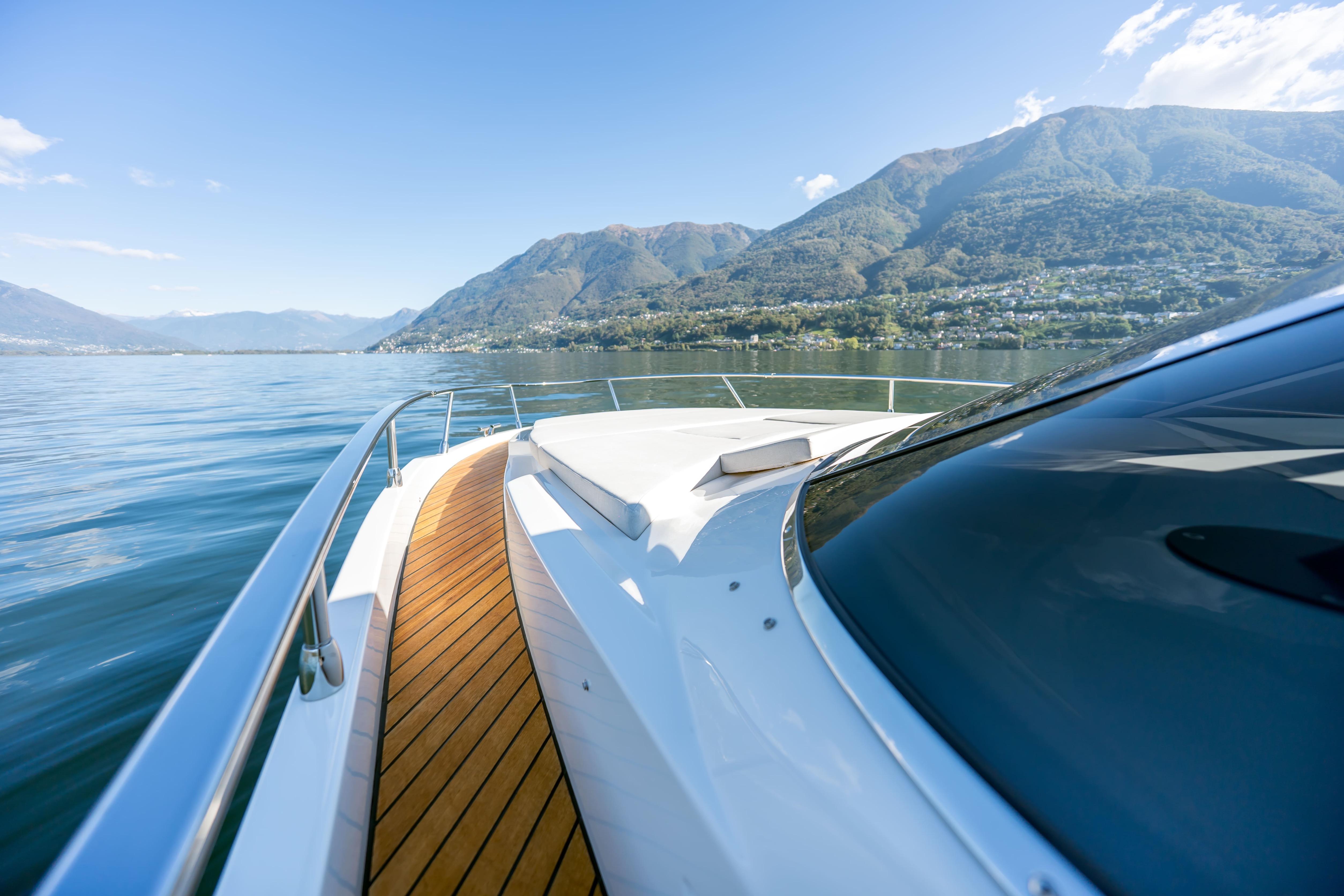 Luxury yacht FIM 340 Regina IB cruising on serene waters, scenic mountain backdrop.
