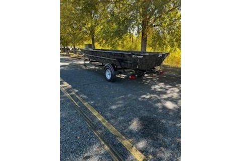2026 Tracker Grizzly 1754 Utility boat on trailer, parked under trees.