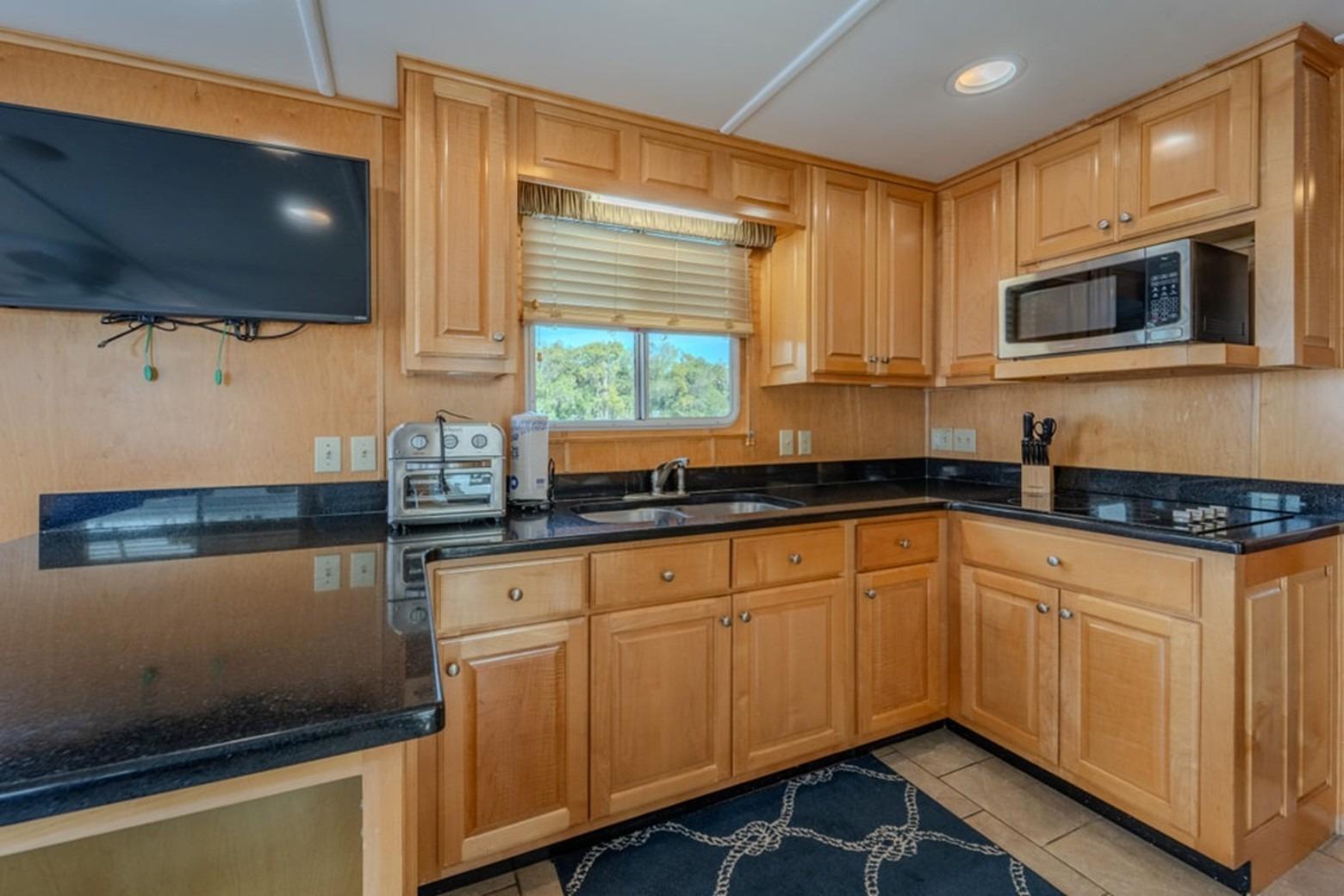 Modern kitchen in 2014 Sunstar Houseboats 55, featuring wood cabinets and black countertops.