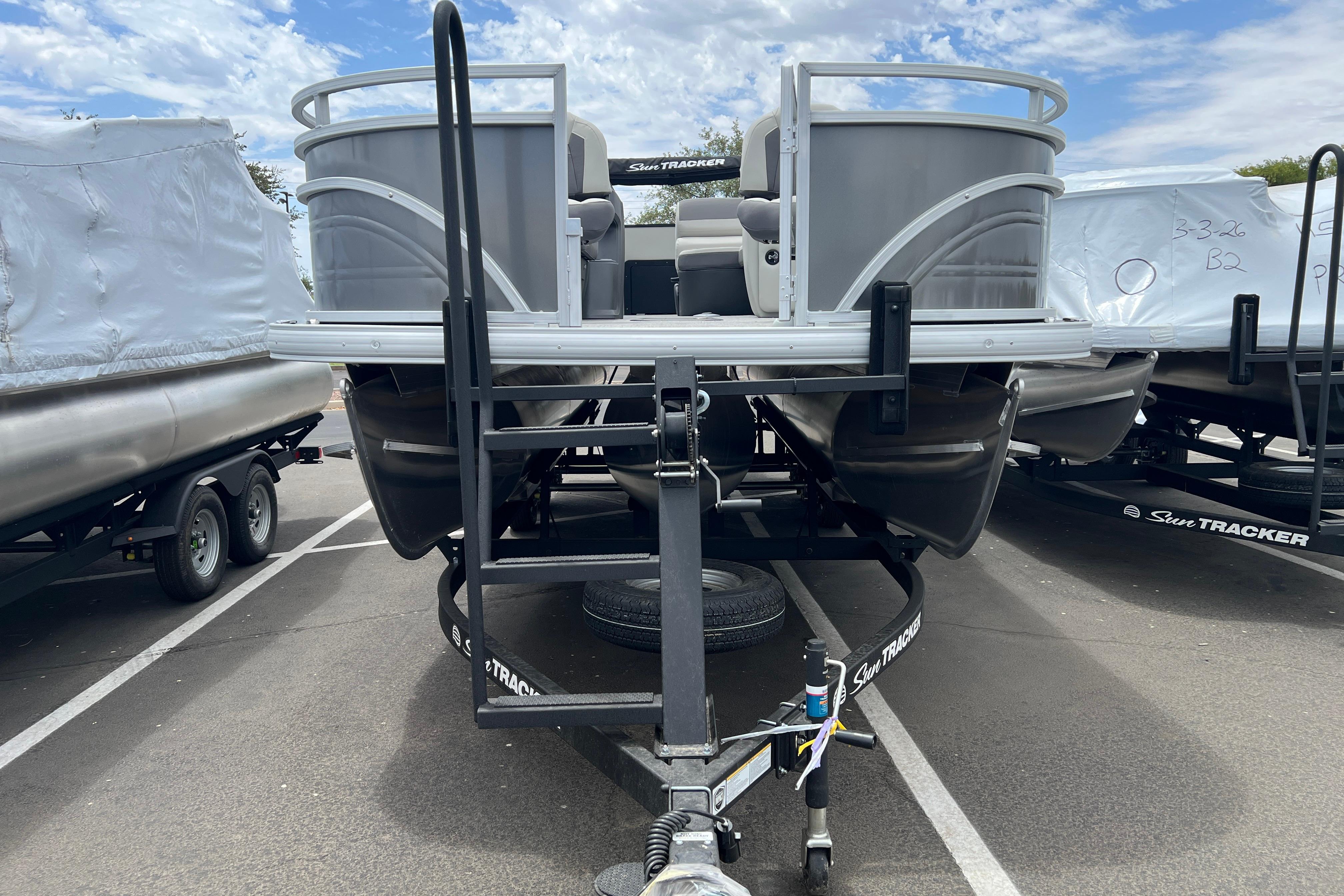 2026 Sun Tracker Fishin' Barge 22 XP3 pontoon boat on trailer, parked outdoors.