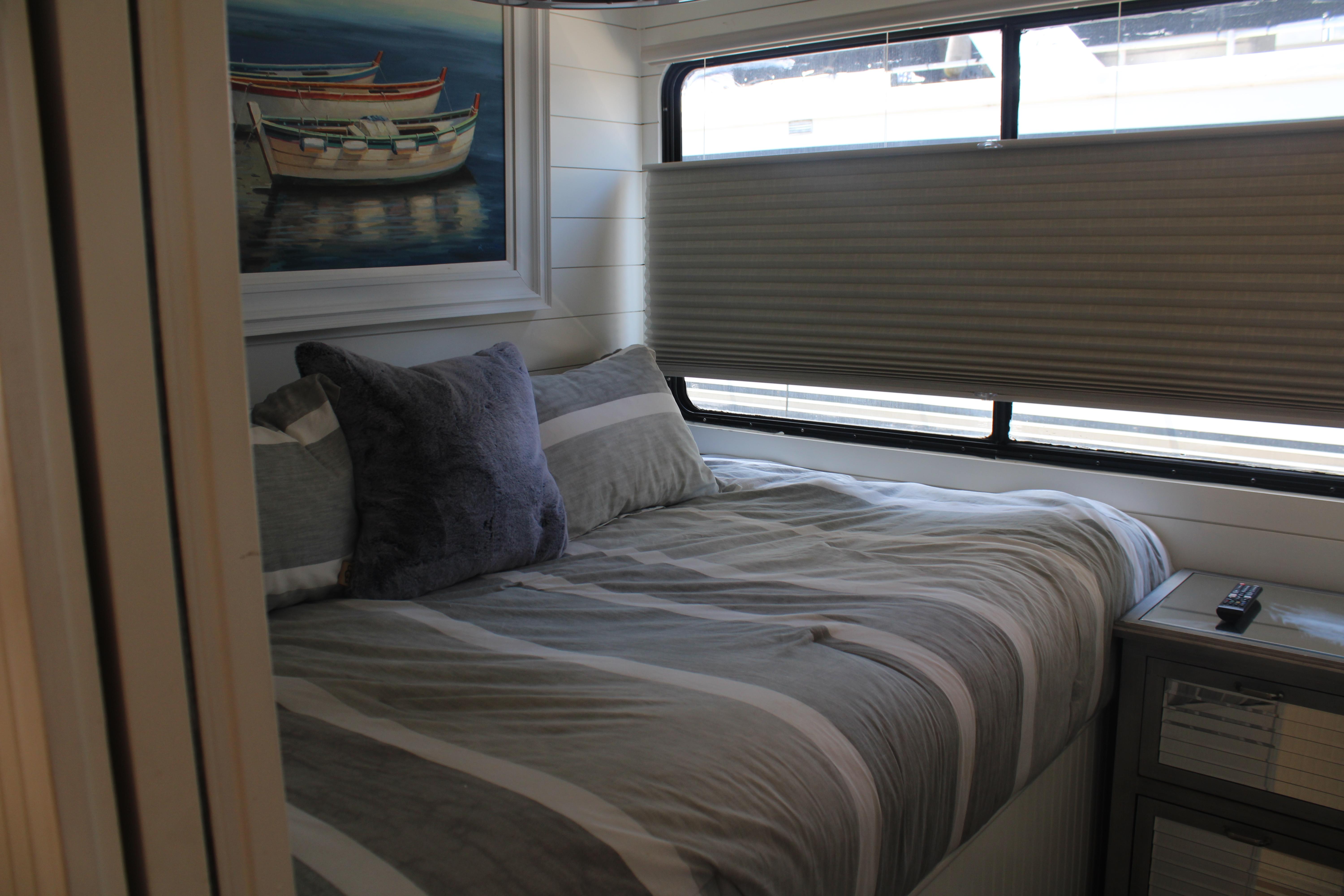 Cozy bedroom in 1992 Sumerset 66 houseboat with striped bedding and nautical artwork.