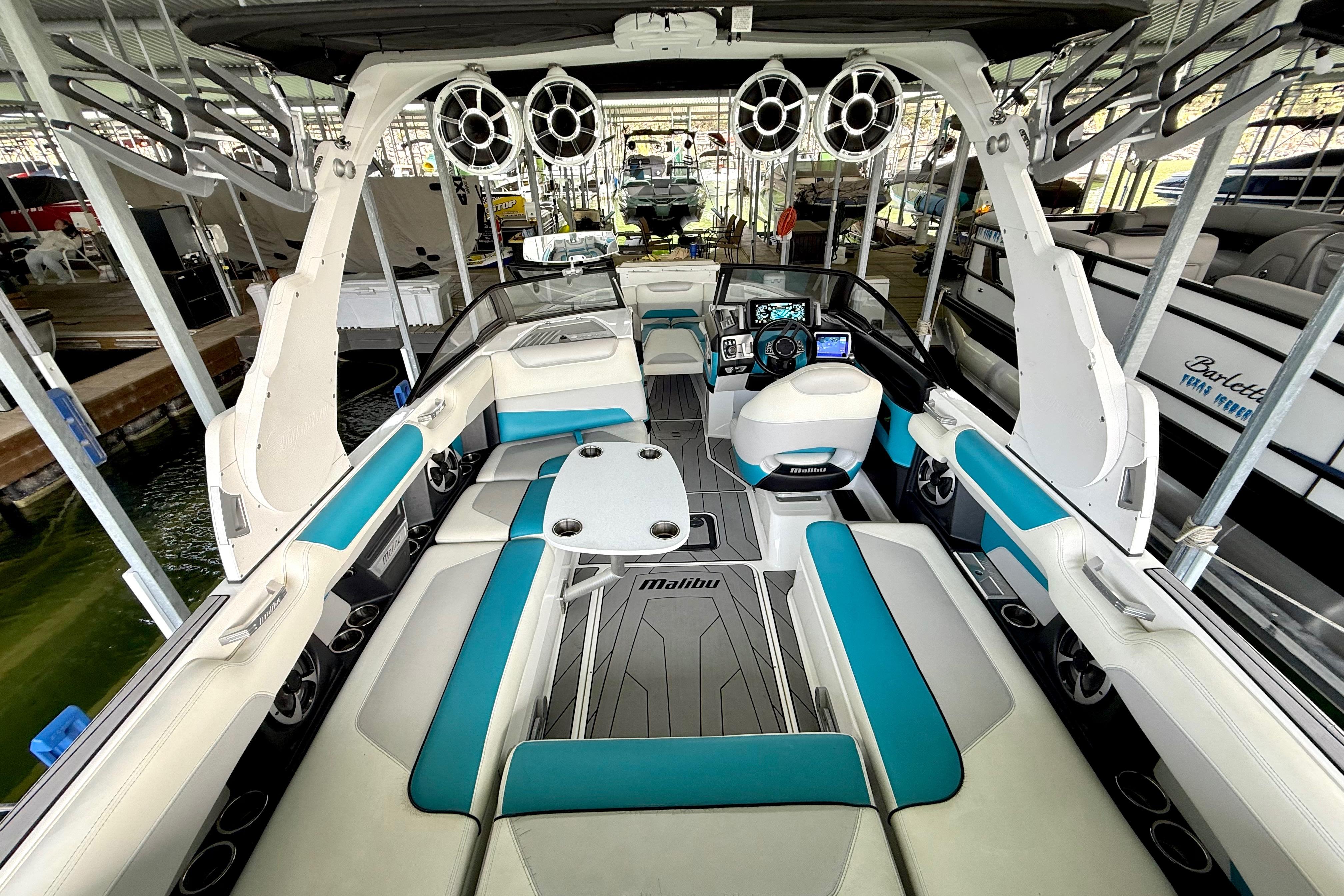 2017 Malibu M235 boat interior with teal and white seating, advanced dashboard, and speakers.