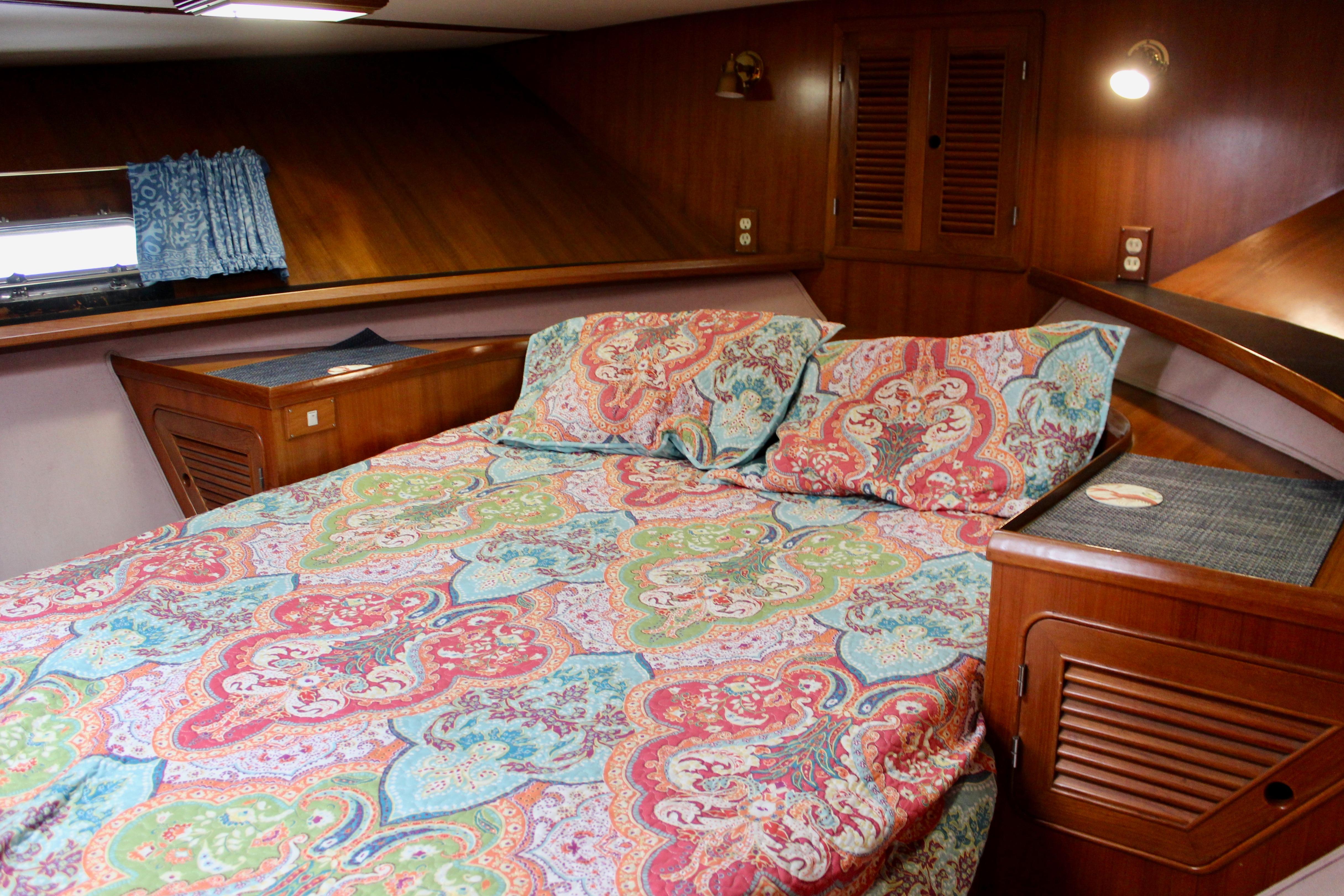 Cozy cabin interior of 1986 Kha Shing Spindrift 46 with colorful bedding and wood paneling.
