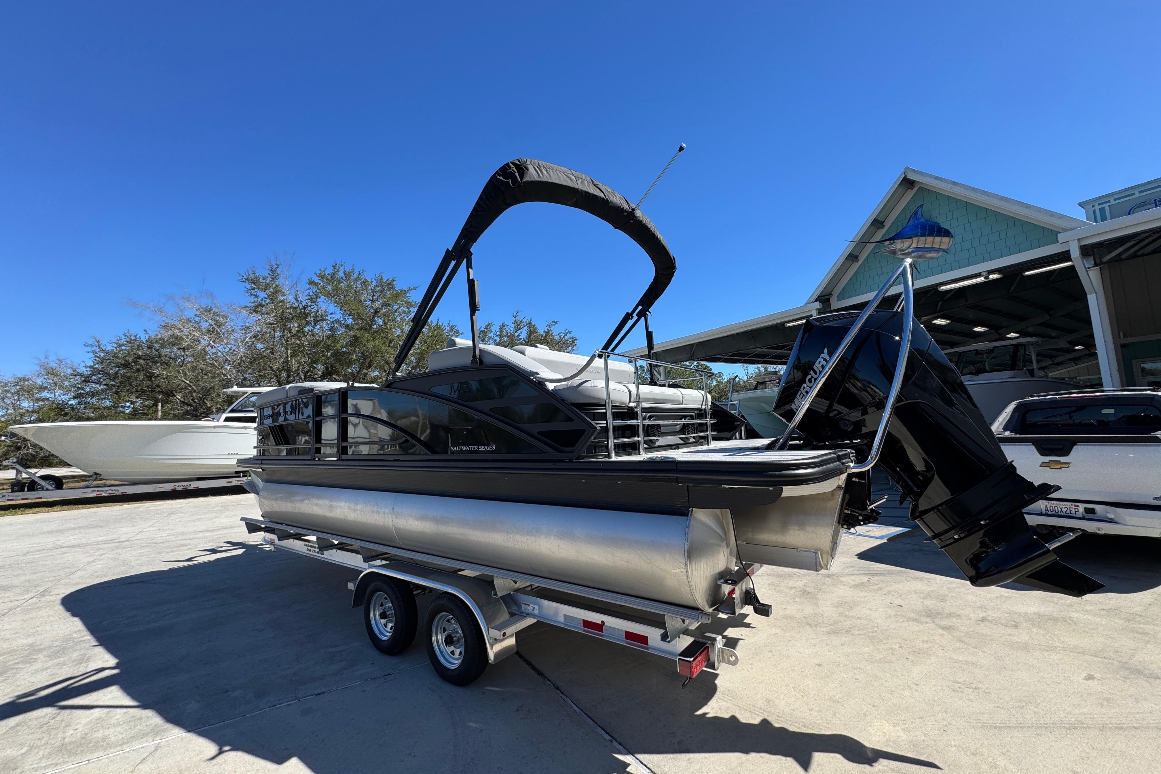 2026 Bennington 22 MSB pontoon boat on trailer, parked outdoors under clear blue sky.