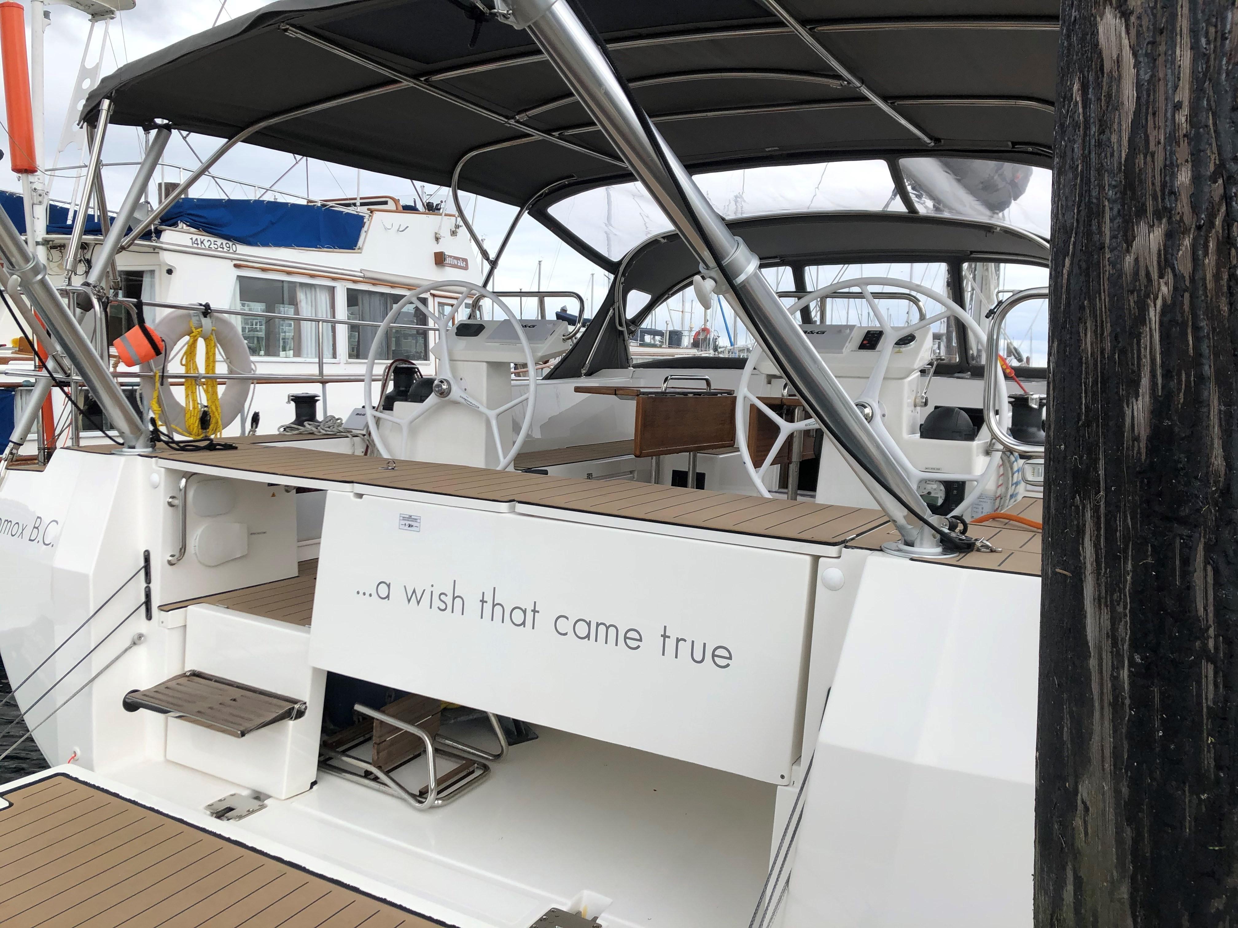 2019 Bavaria C45 Style yacht with dual steering wheels and canopy, docked at marina.
