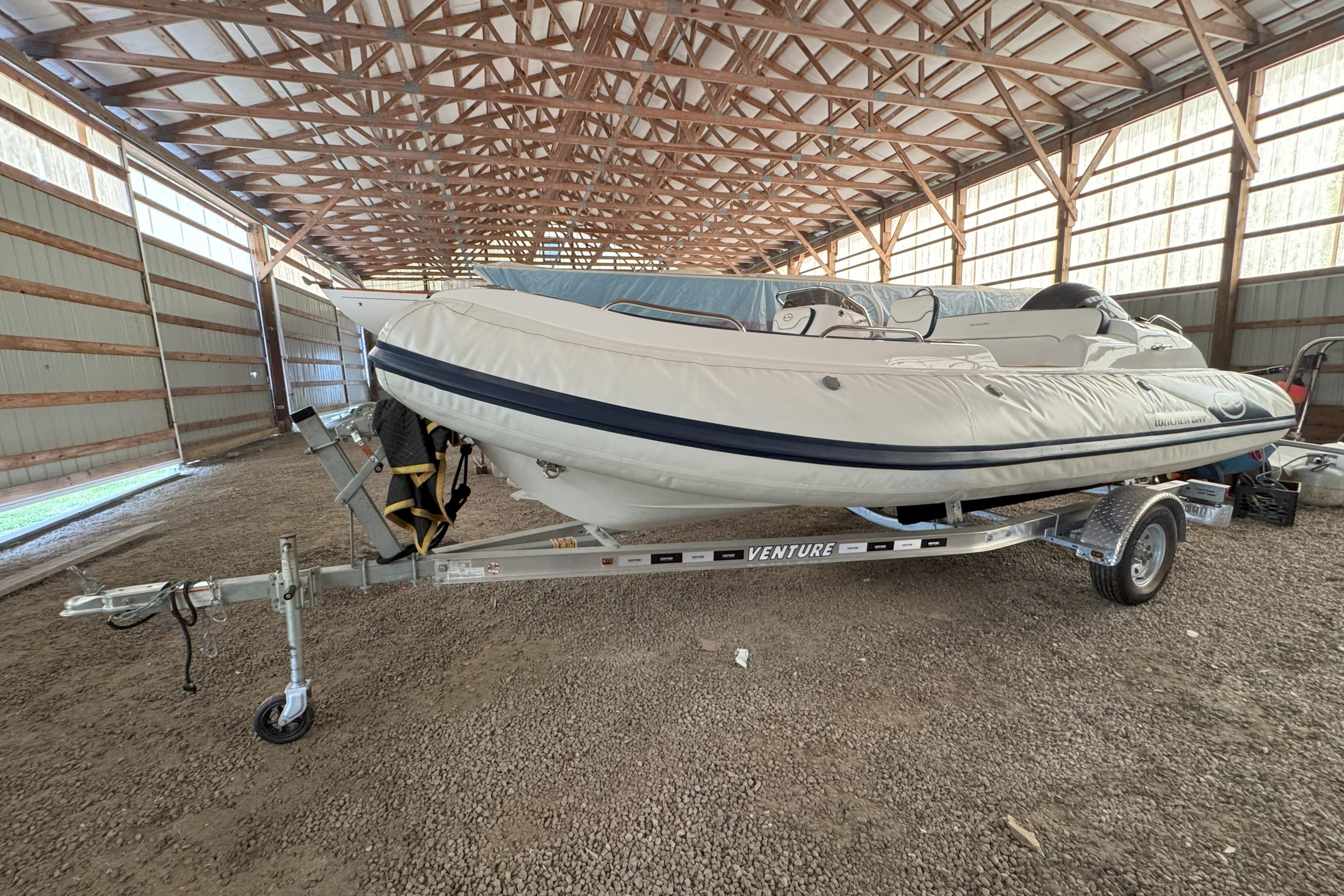 2024 Walker Bay Generation 525 boat on trailer in a spacious indoor storage facility.