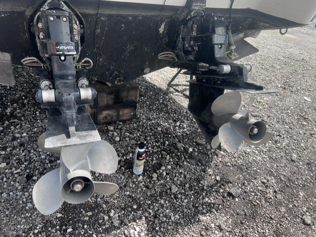Two boat engines with propellers on a gravel surface.