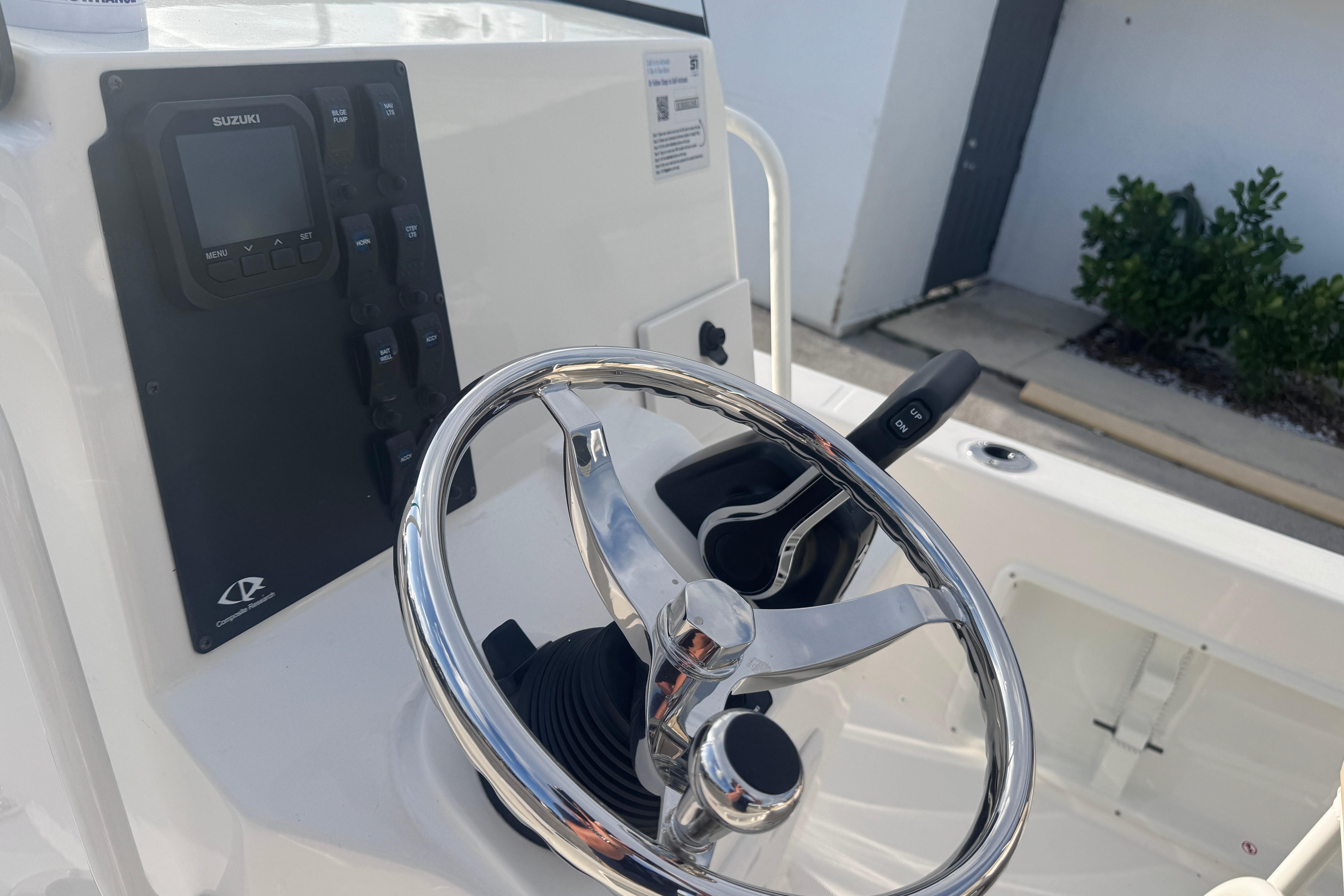 Steering console of 2026 Sundance DX22 boat with Suzuki controls and chrome wheel.