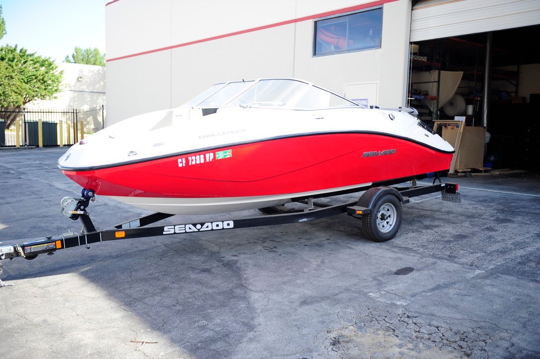 A red boat, model Challenger 180, is on a trailer in front of a building.