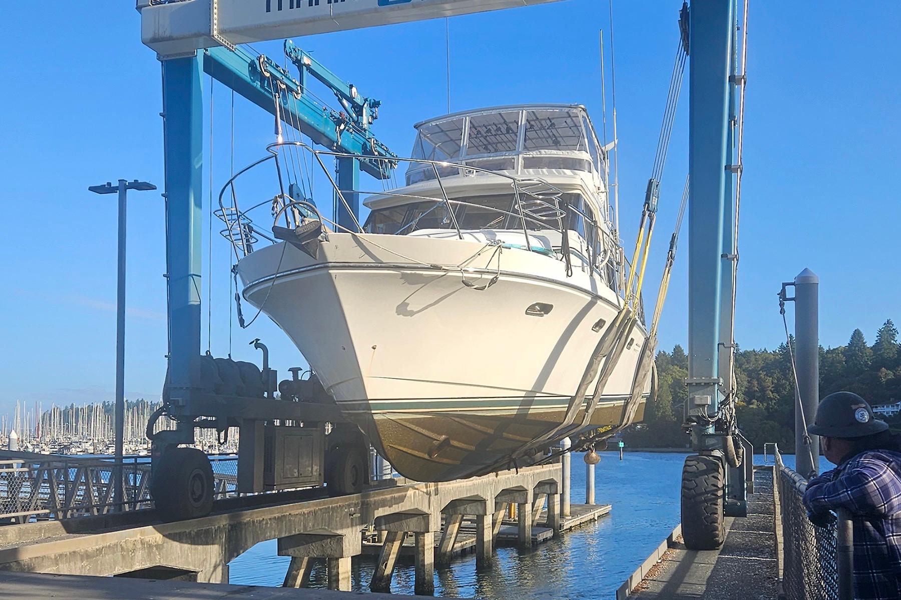 A 1995 Symbol 55 yacht being lifted by a boat hoist at a marina.