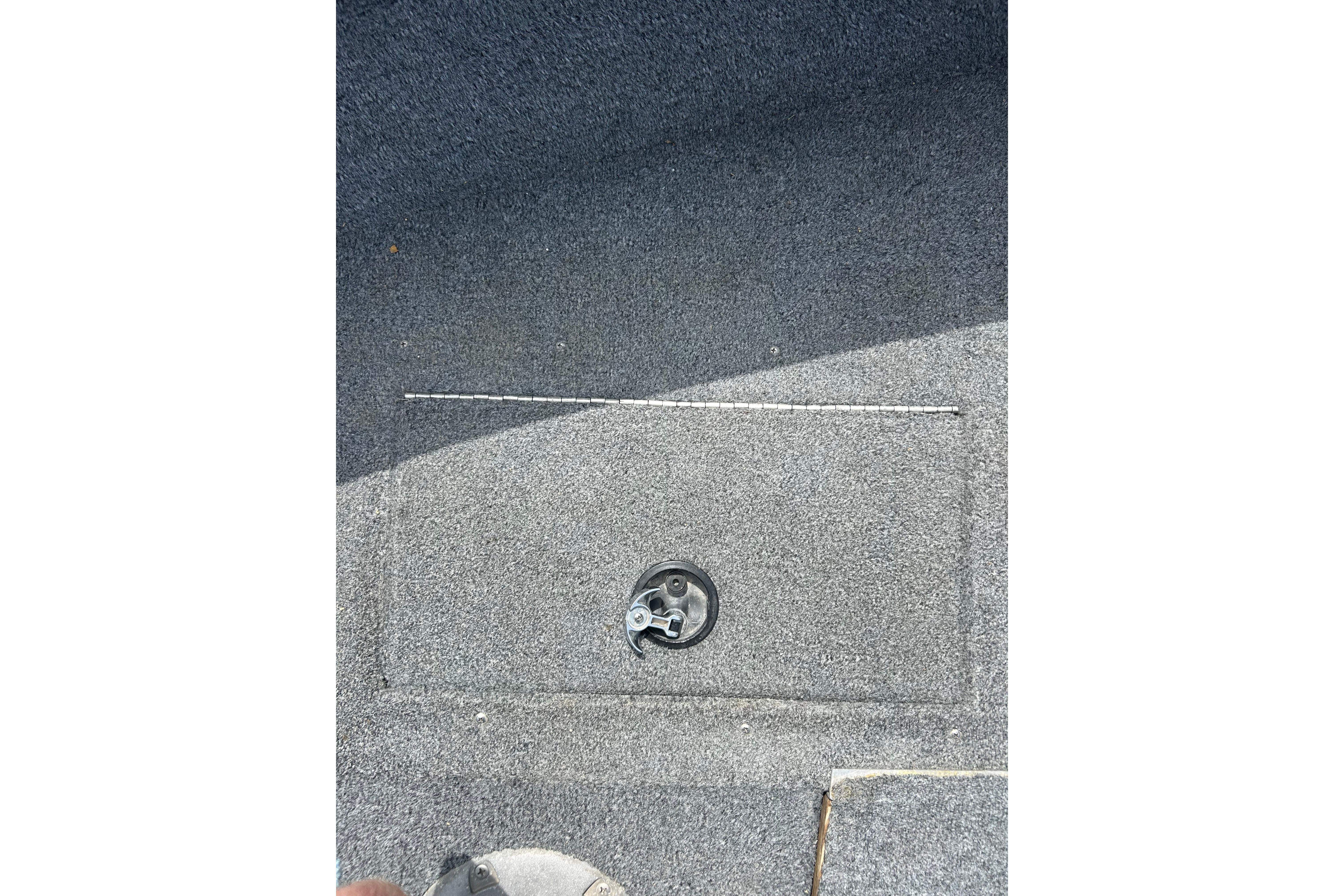 Carpeted deck of a 2008 Lund 1850 Fisherman boat with a hatch and latch.