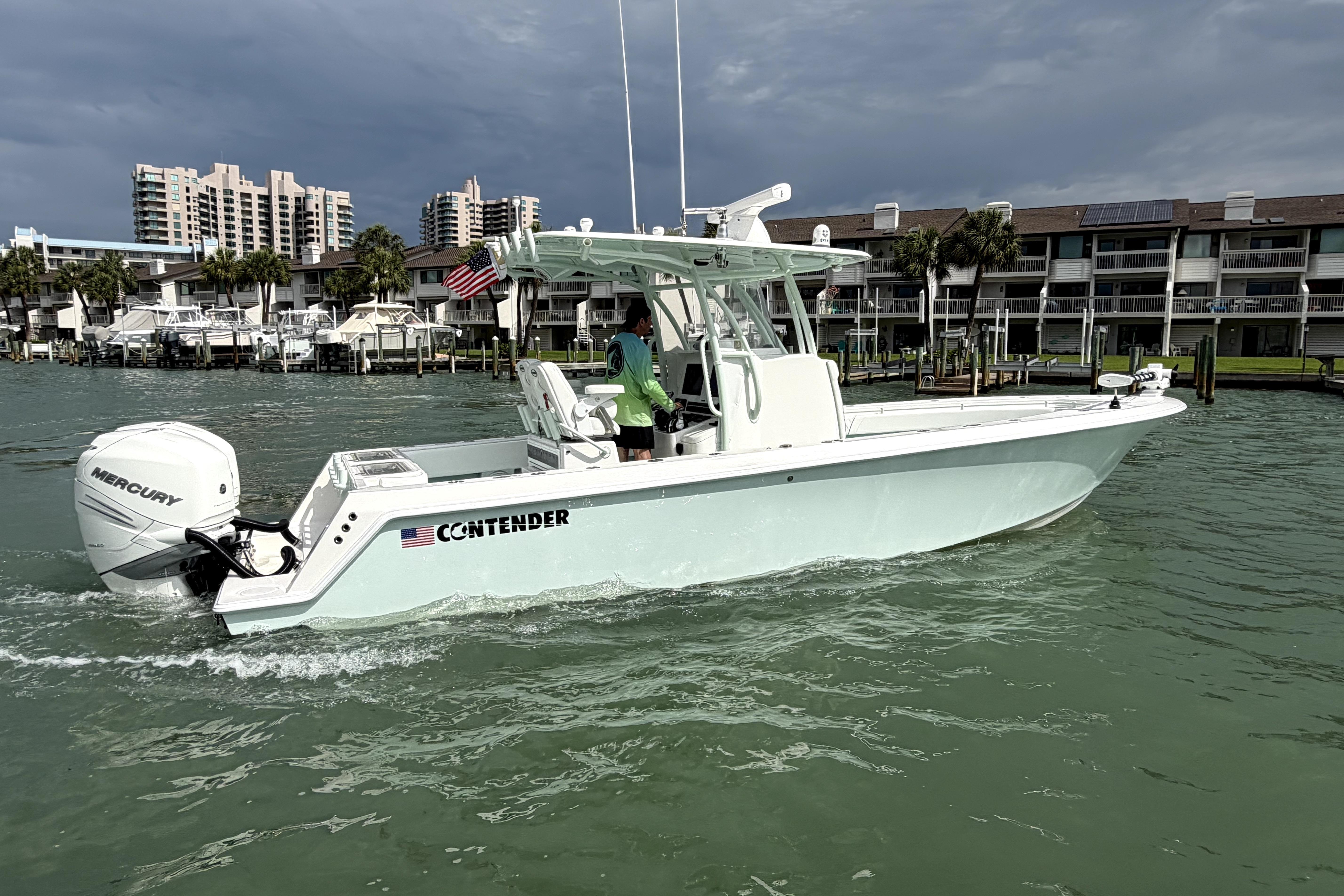 2019 Contender 30 ST boat cruising in a marina with buildings in the background.